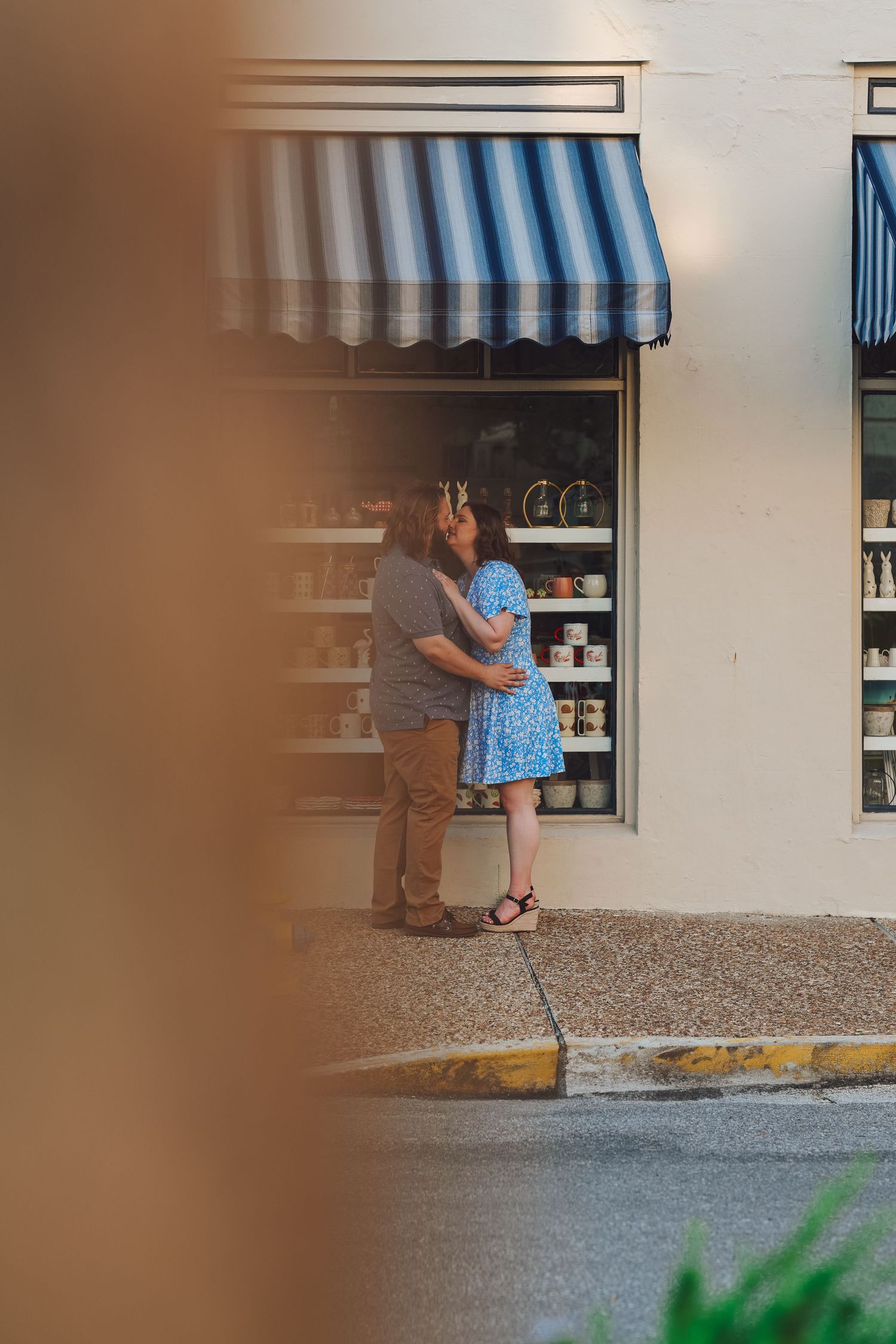 Two people share a tender moment through a drive-through window at a small business establishment.