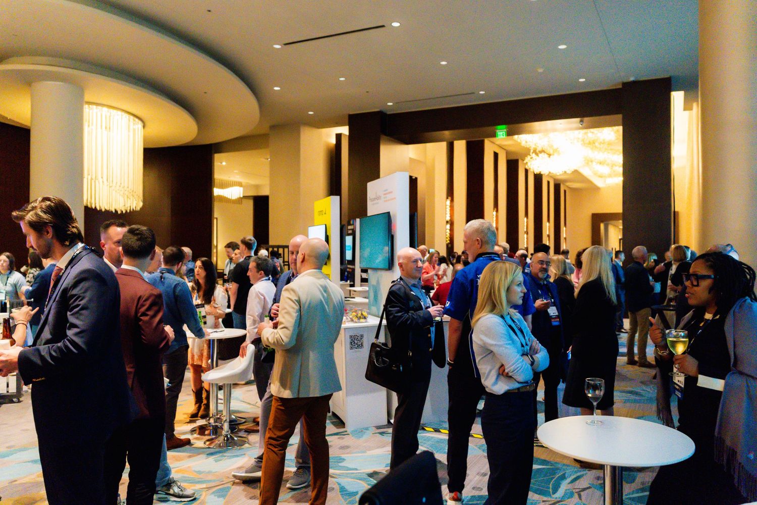 Professionals networking in an elegant hotel ballroom during a business conference event.