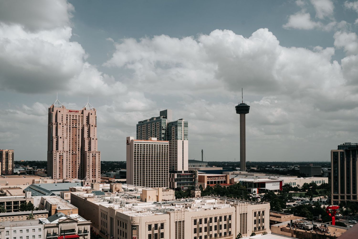 San Antonio skyline featuring the Tower of the Americas and downtown skyscrapers under a partly cloudy sky.