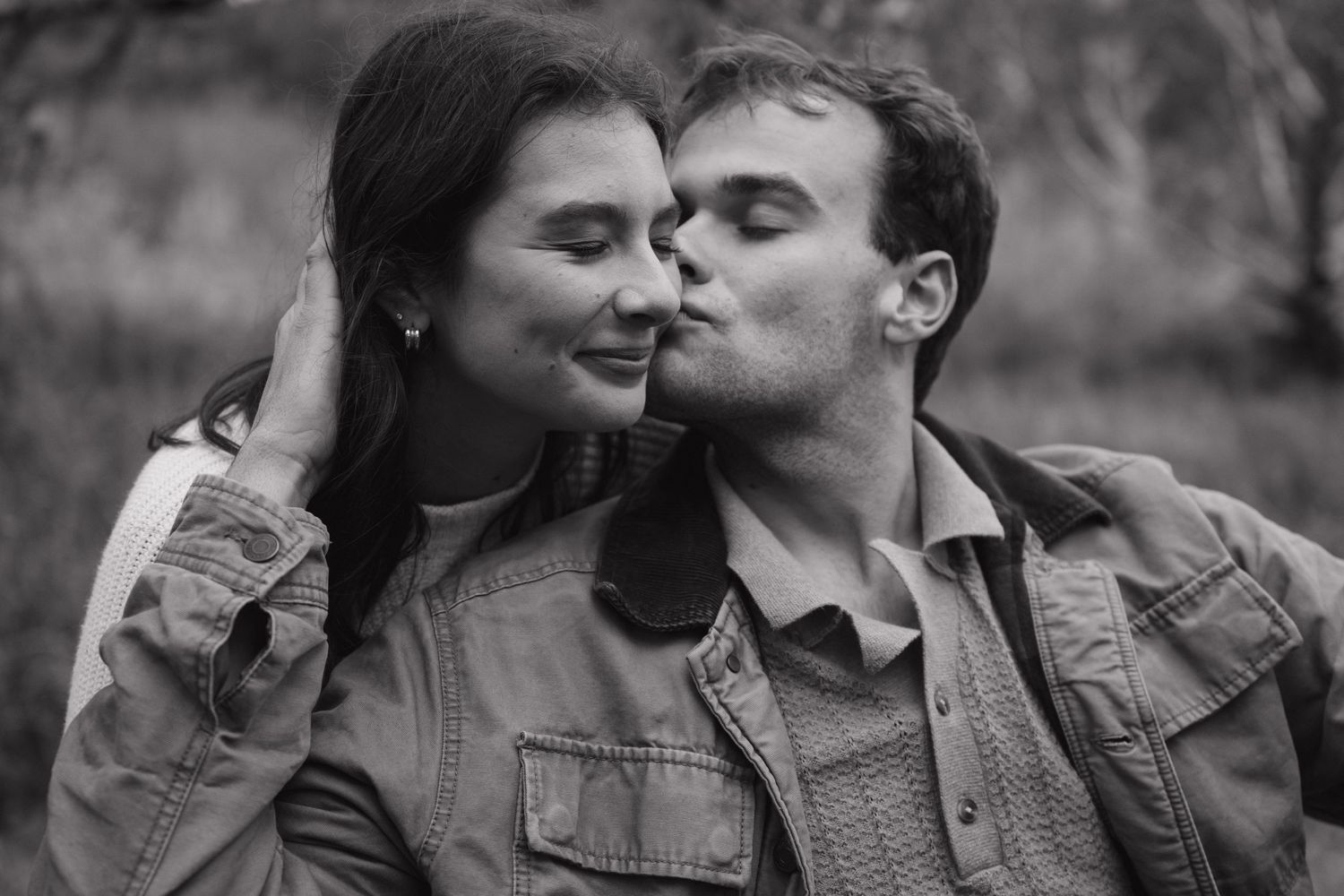 A romantic black and white portrait of a couple sharing an intimate moment outdoors while wearing denim jackets.