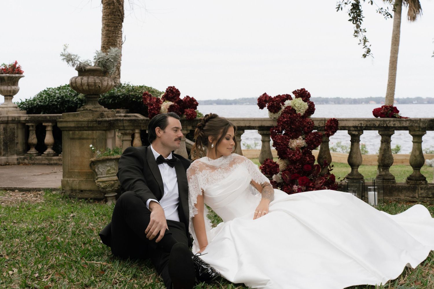 Newlywed couple shares romantic moments along a waterfront balustrade during their wedding photoshoot.