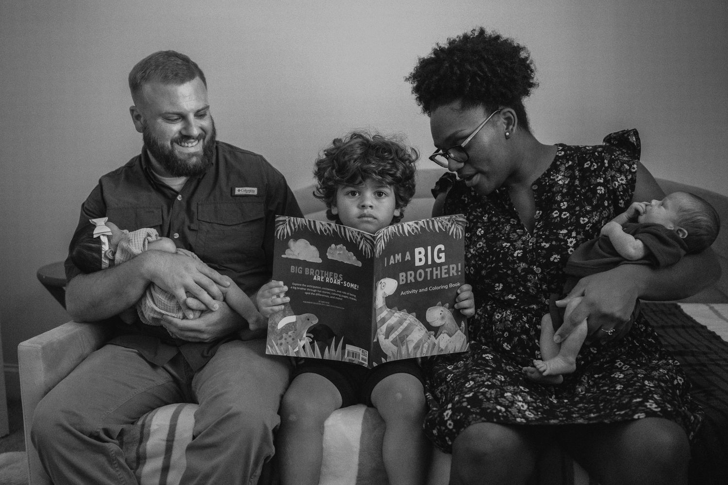 A family reads a children's book together while sitting on a couch.