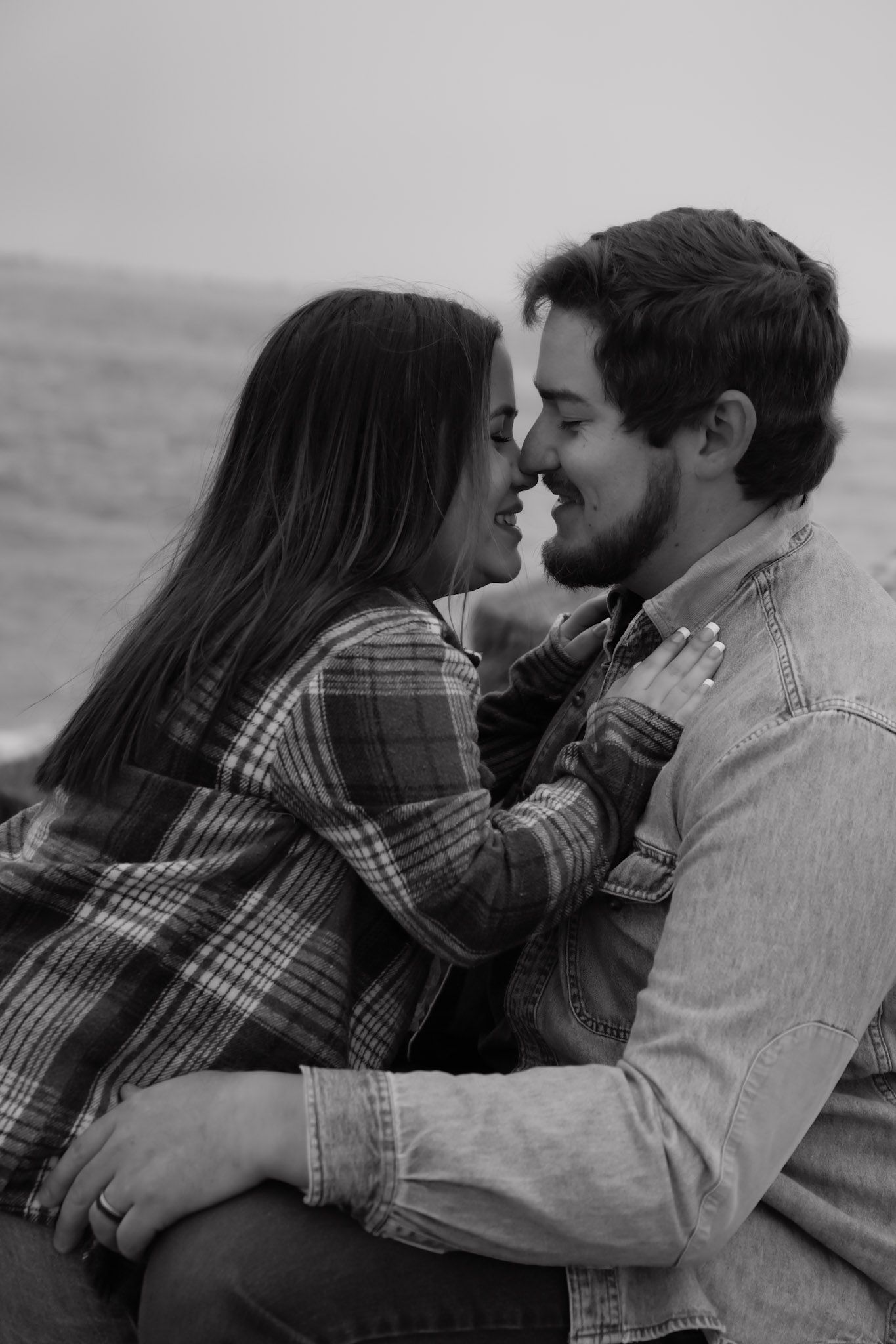 A romantic black and white photo series showing a couple in plaid and denim embracing and sharing tender moments.