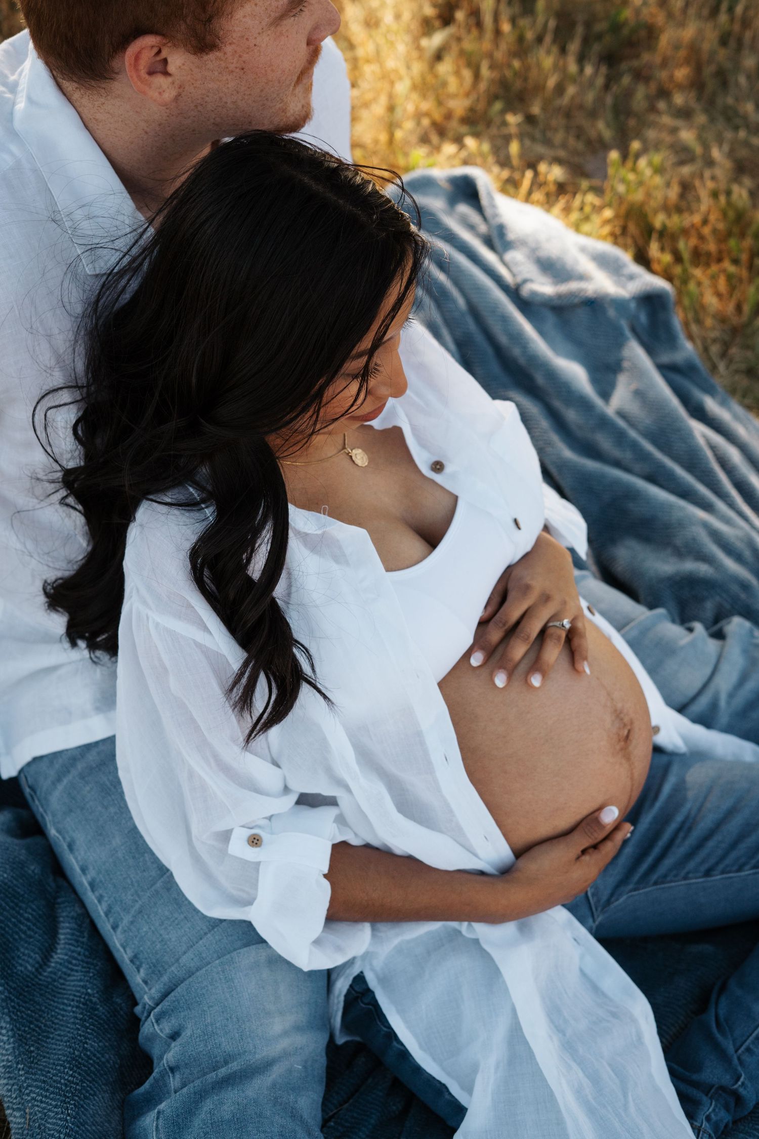 A series of maternity photos showing a pregnant woman in a white shirt resting on a blue blanket outdoors.