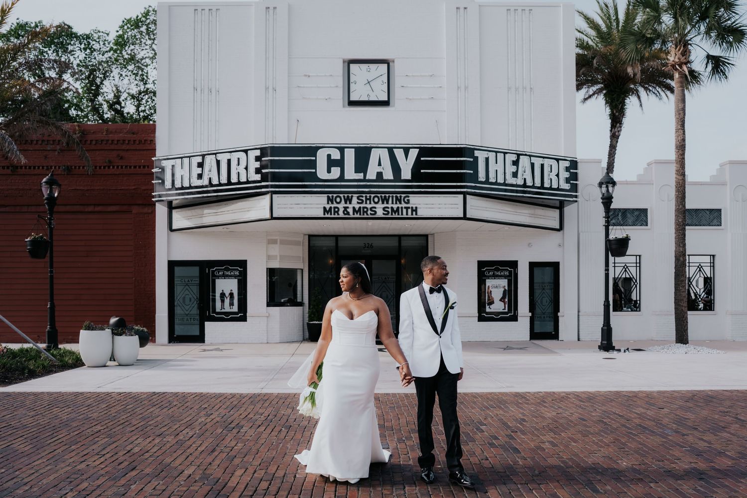 Stylish wedding couple poses in front of the historic Clay Theatre with its classic white facade and marquee.