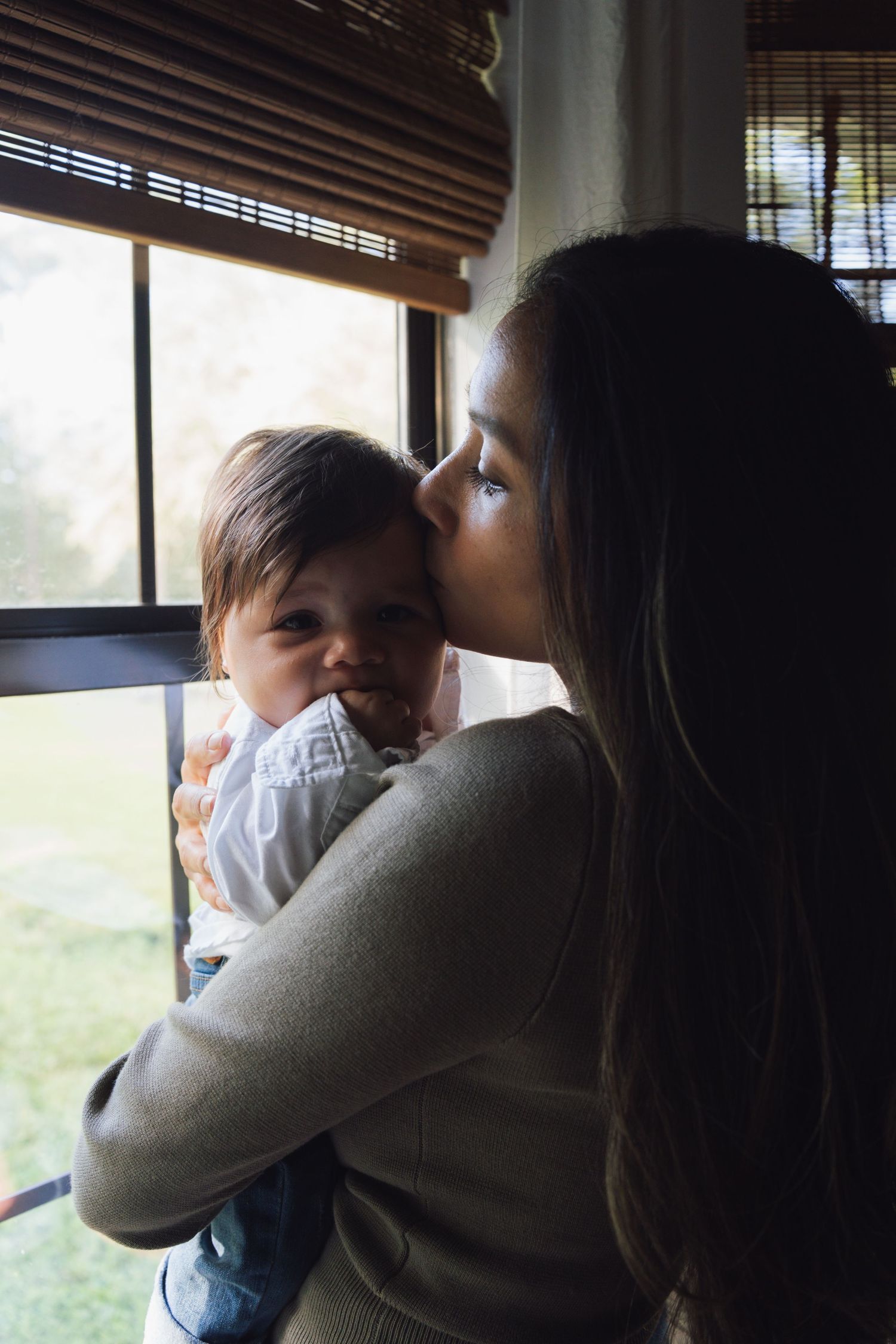 Silhouetted figures share an emotional embrace near a window with bamboo blinds.