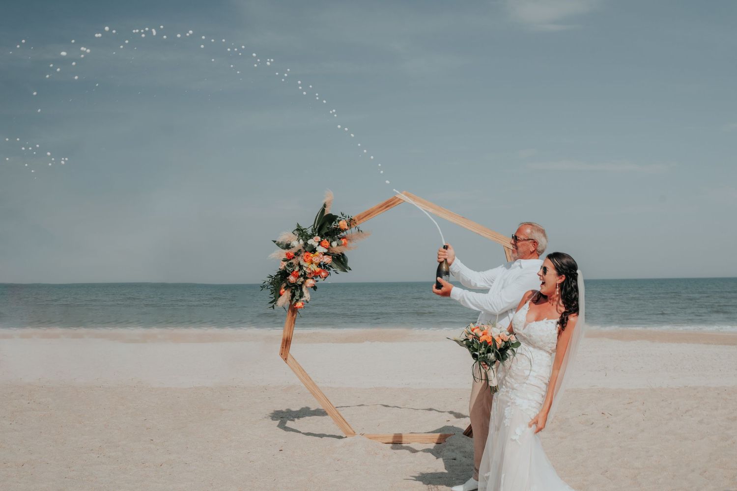 A joyful dance sequence captured on a serene beach with the ocean and cloudy sky in the background.