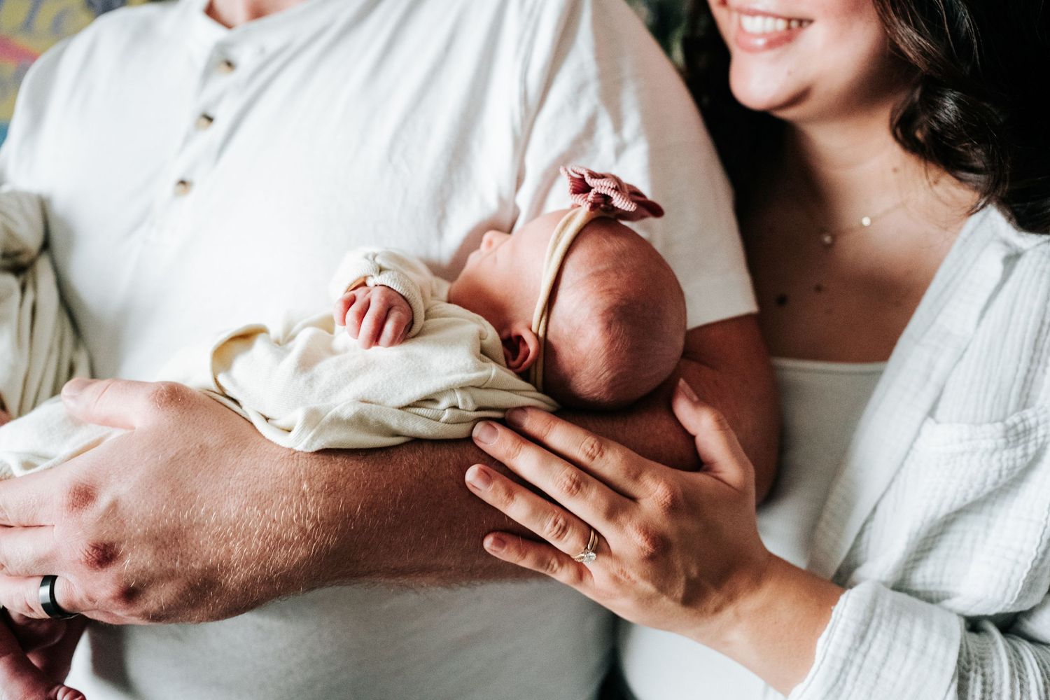 Close-up of newborn baby being cradled in parents' arms.