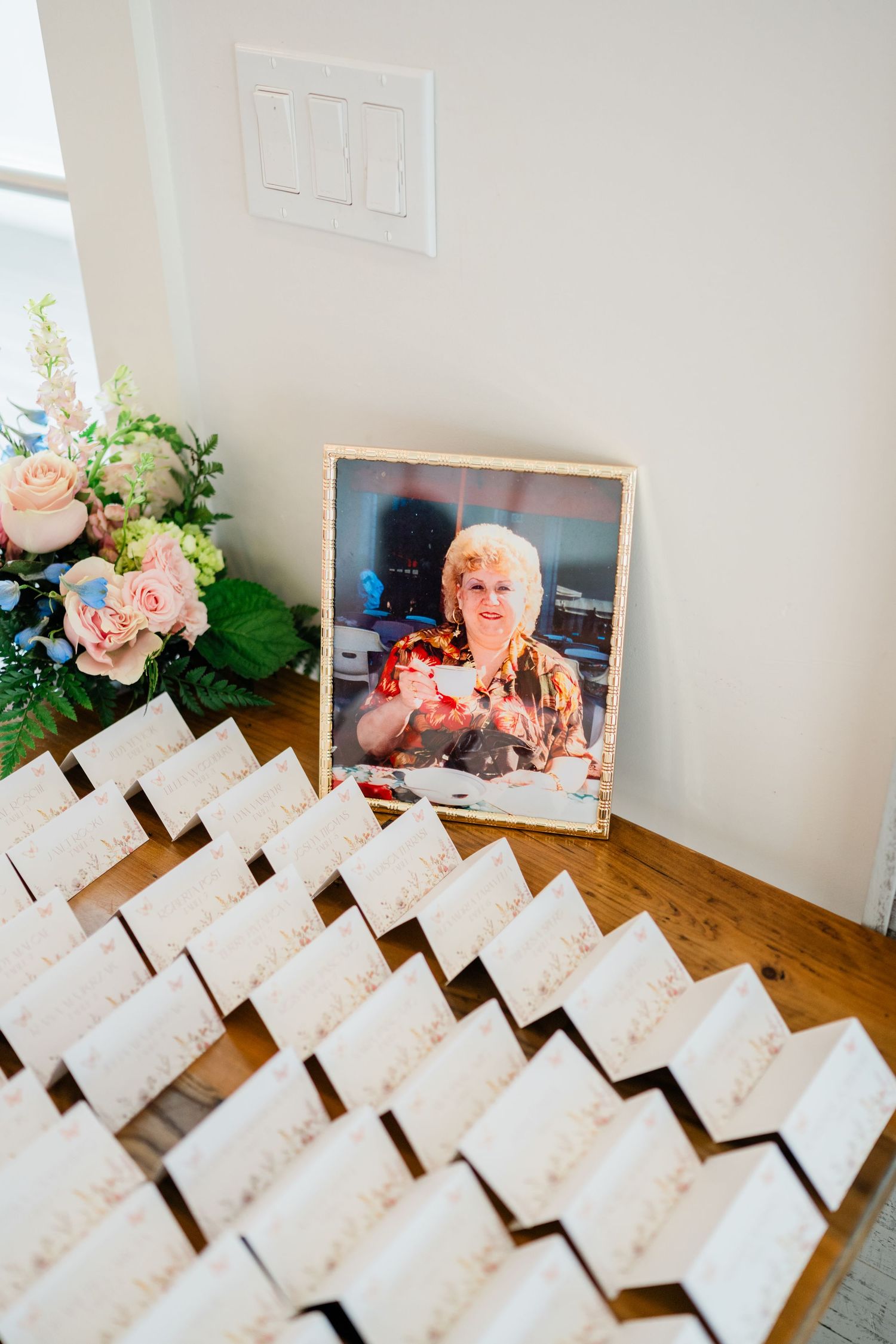 Wedding place cards arranged in neat rows with floral decorations and framed photos.