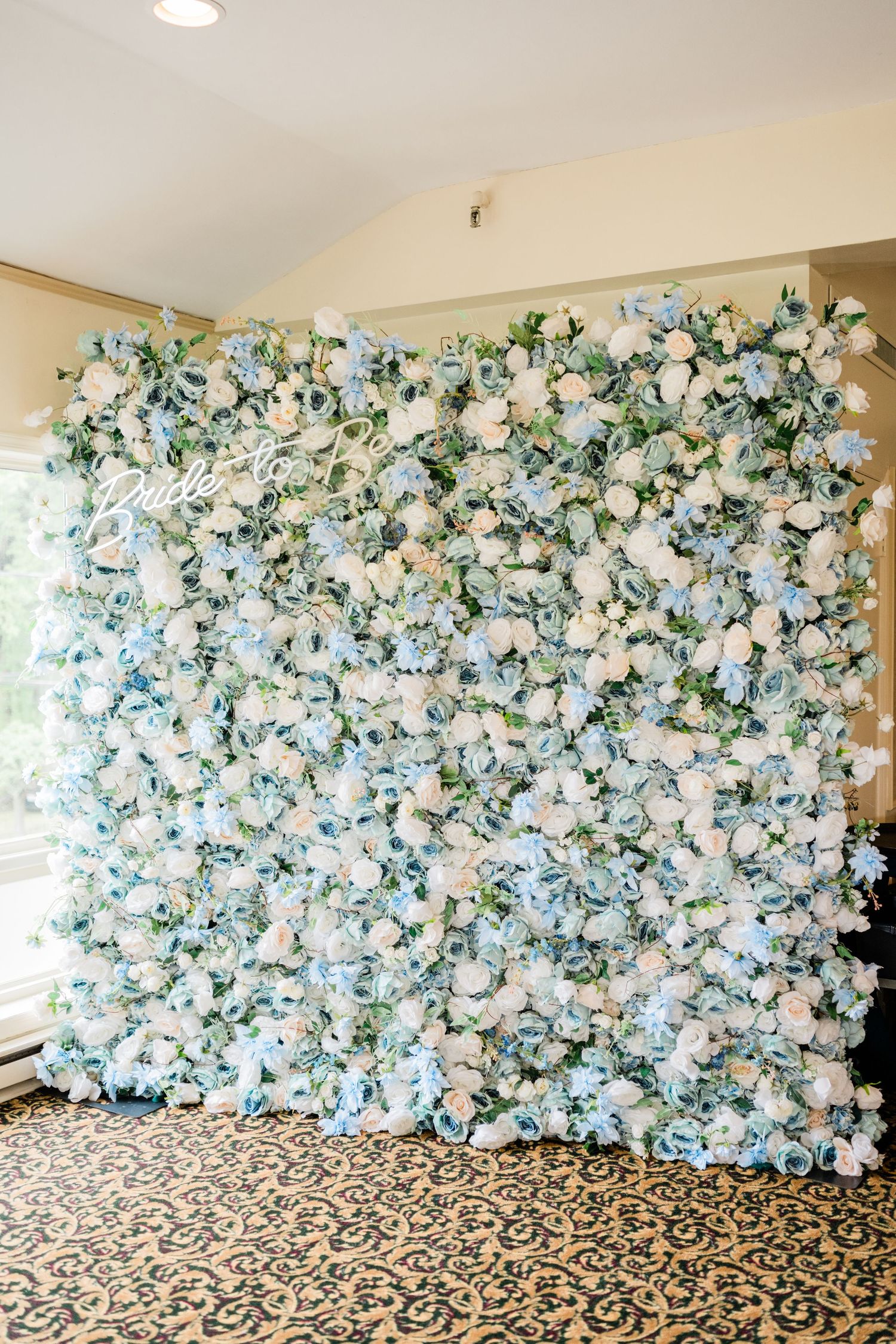 Large floral wall backdrop with white and blue flowers creating a stunning photo opportunity.
