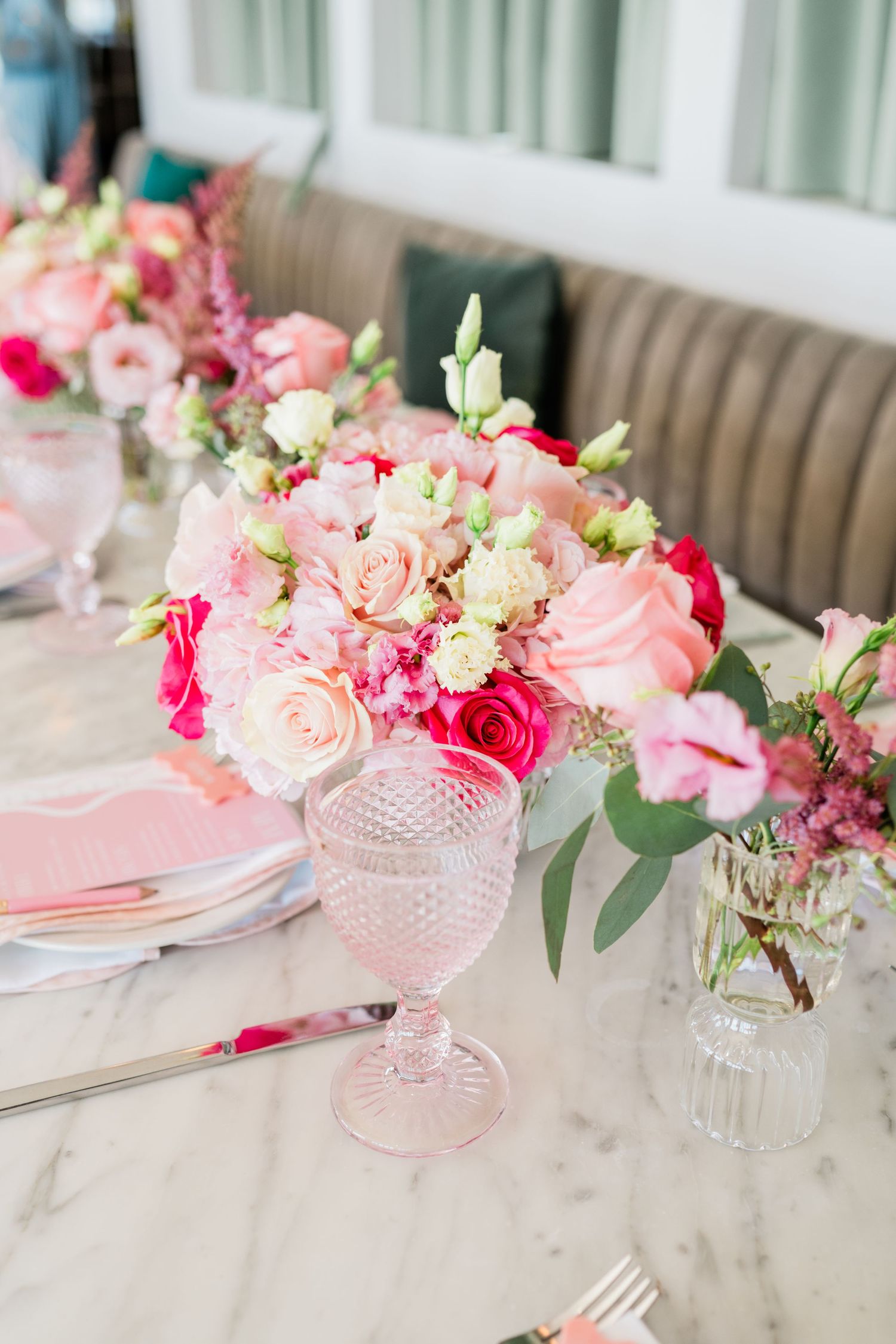 Elegant table setting with pink roses and crystal vases for romantic celebration.