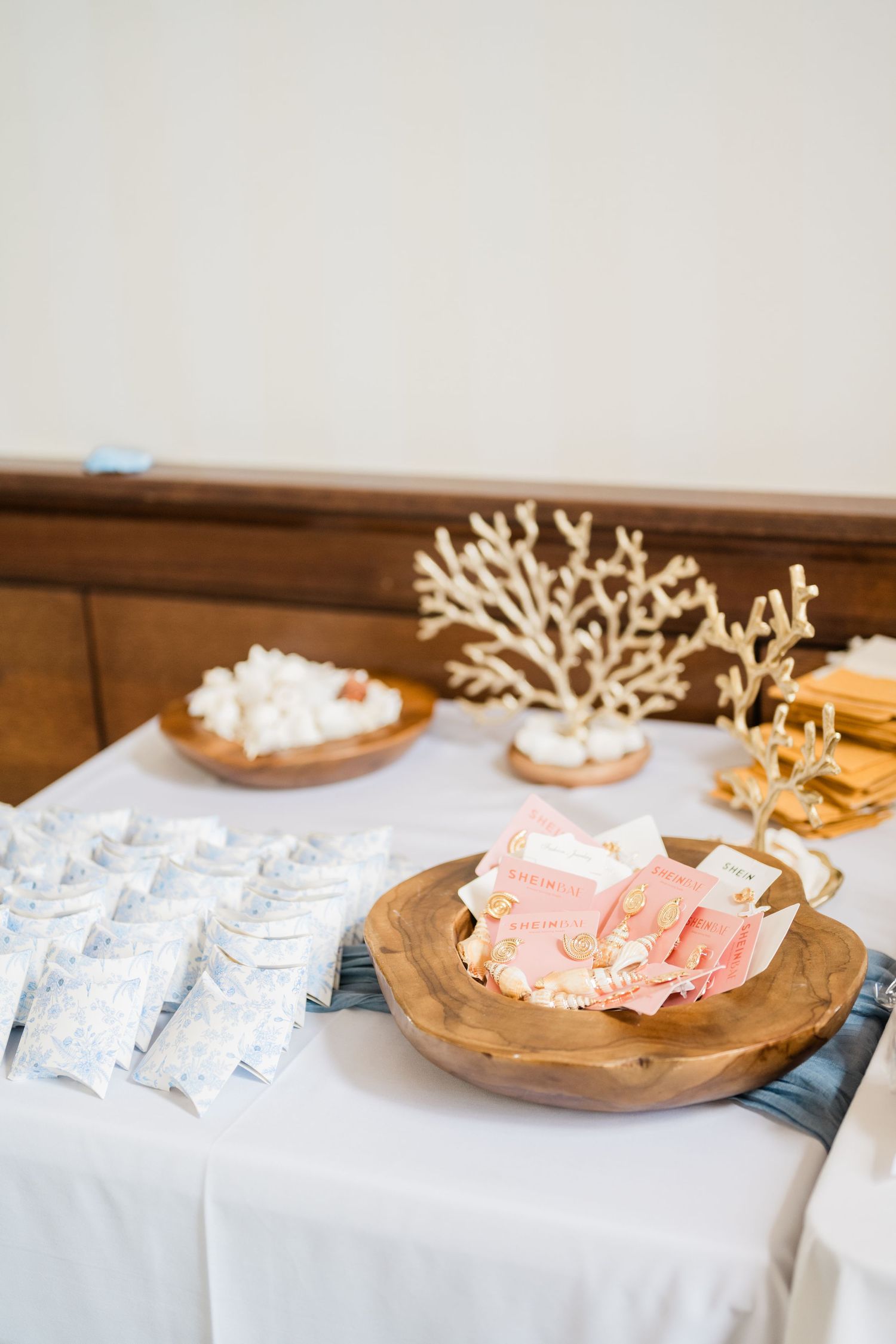 Wedding favors and decorative coral pieces displayed on wooden plates.