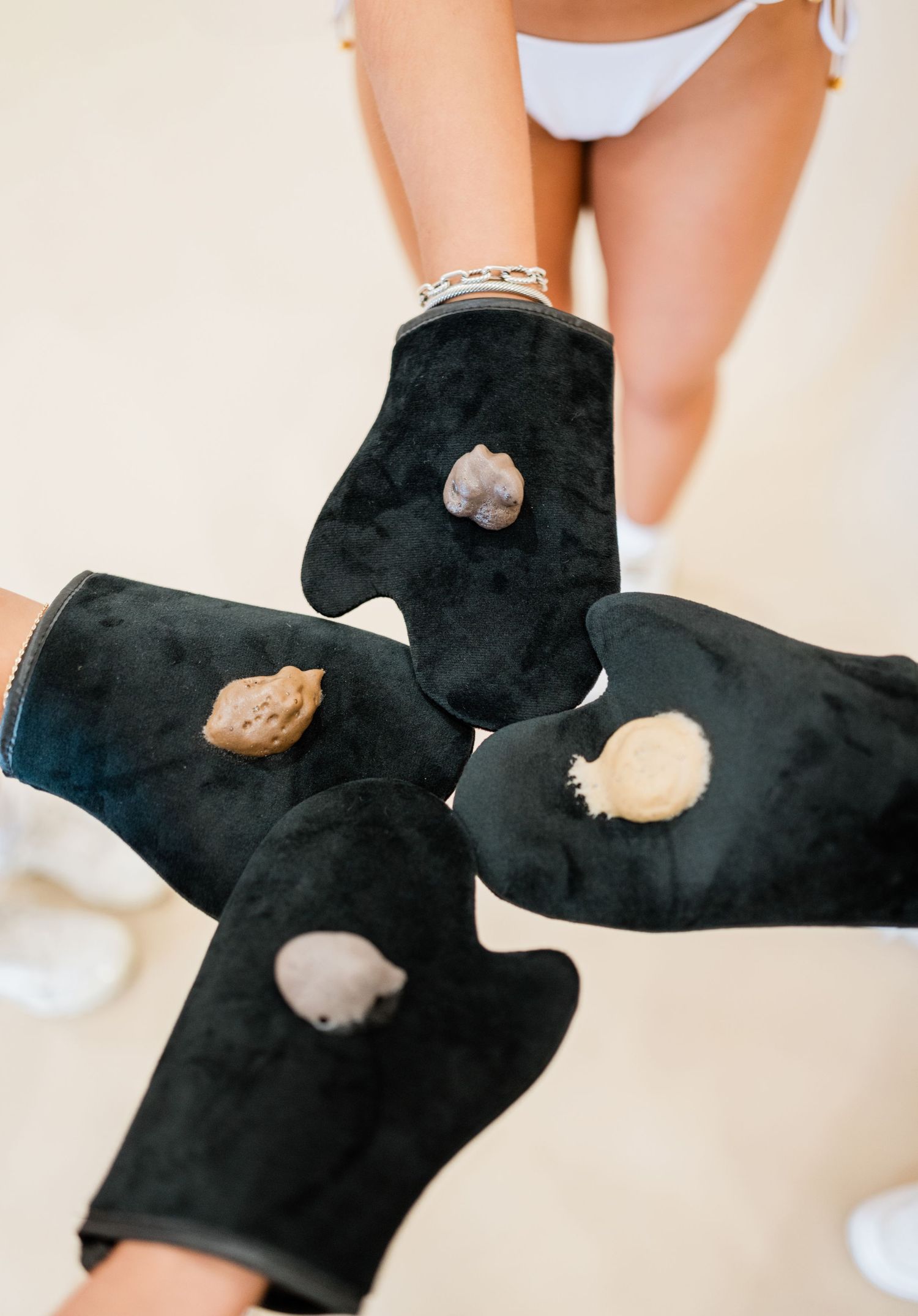 Black gloves with holes displaying product samples against beige background.
