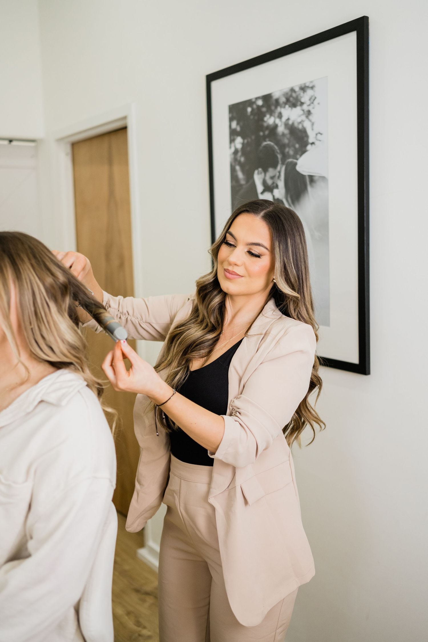 Behind the scenes hair styling session in front of a mirror with black and white artwork.