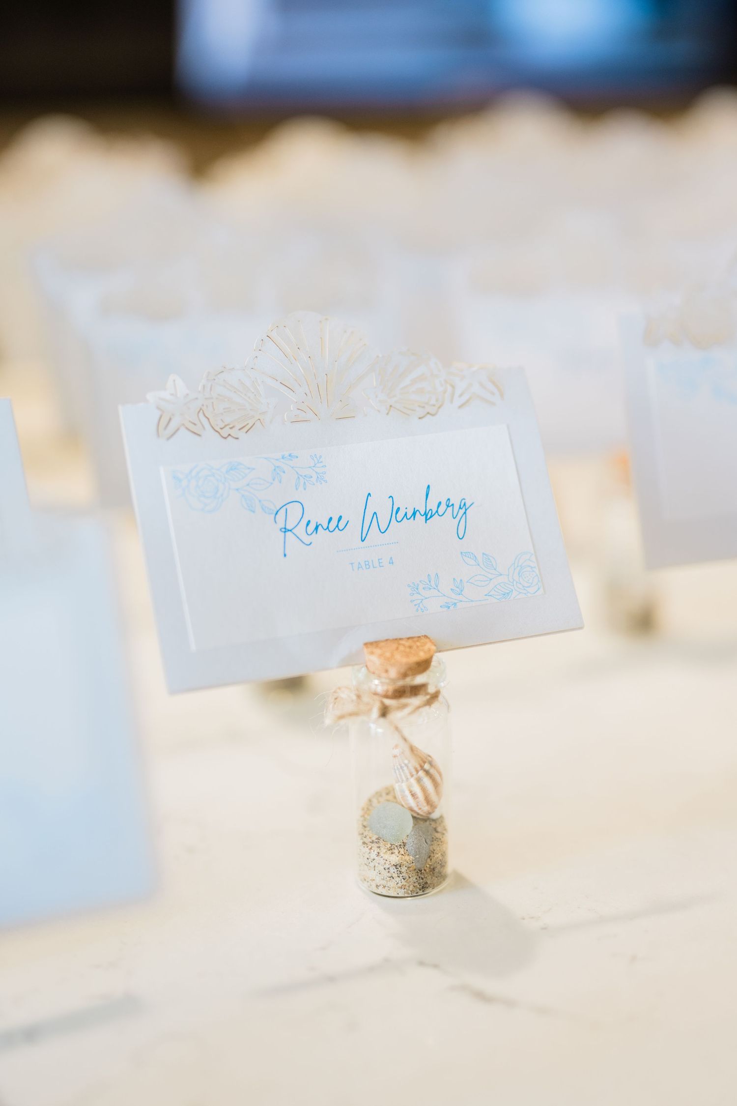Wedding place cards with delicate blue text displayed on a white tablecloth.