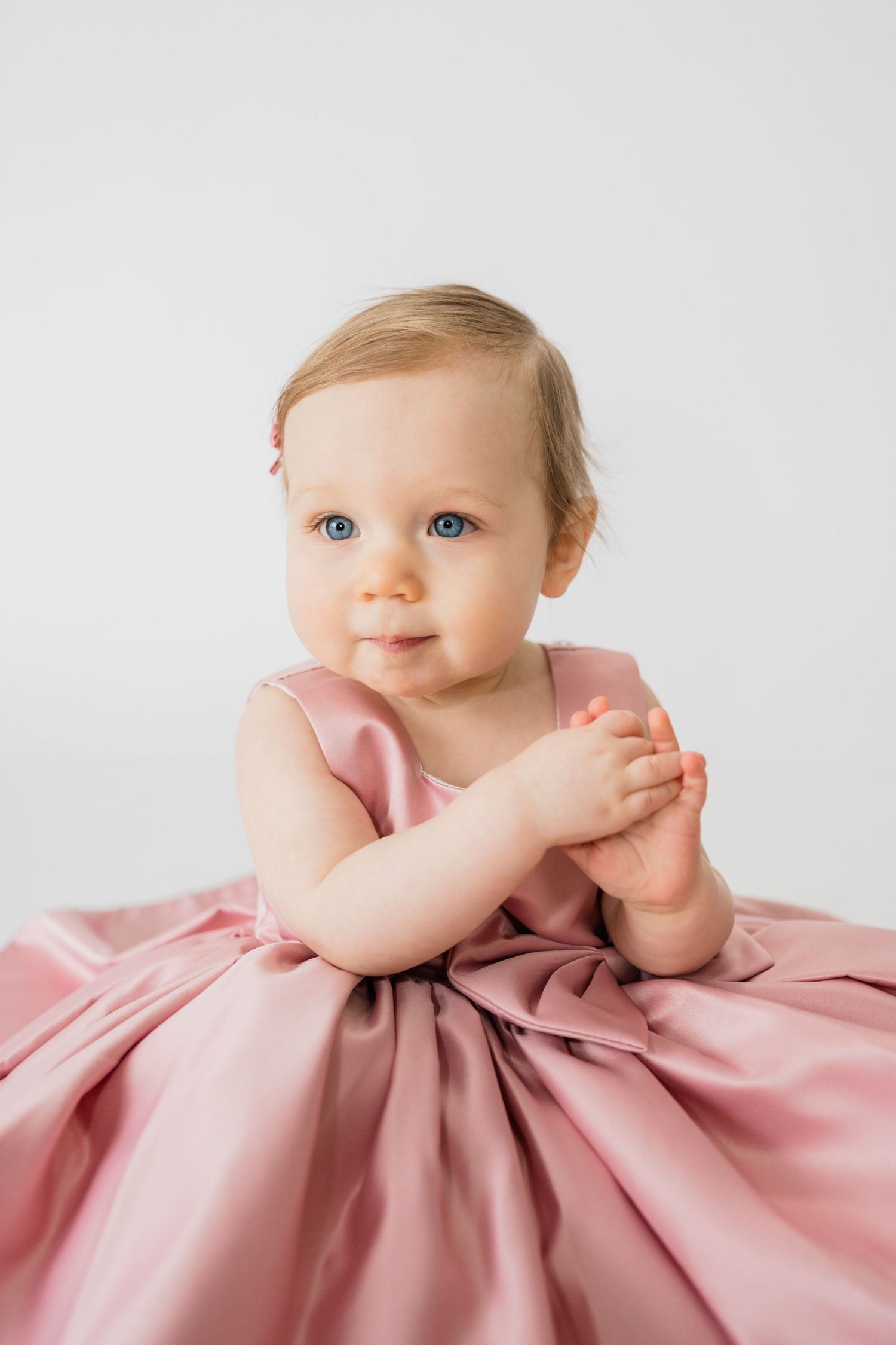 Sweet portrait of a baby in a pink dress against white background.