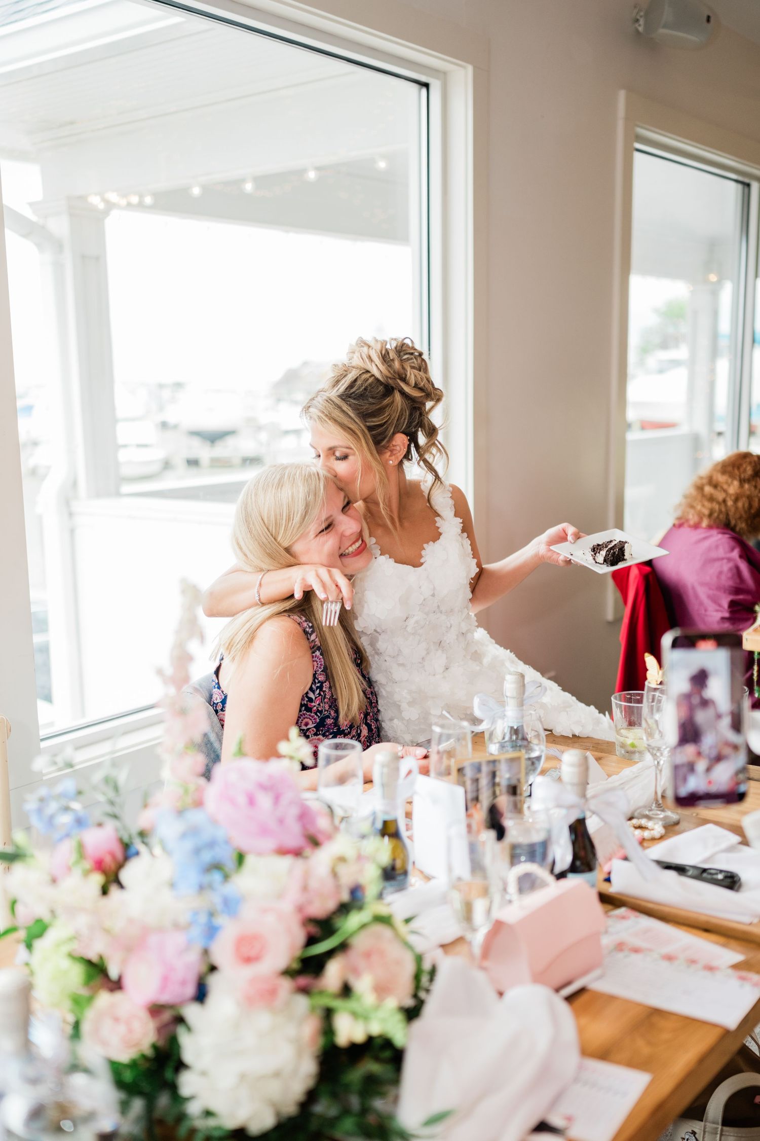 Friends celebrate at a beautifully decorated table with pink and white floral arrangements.