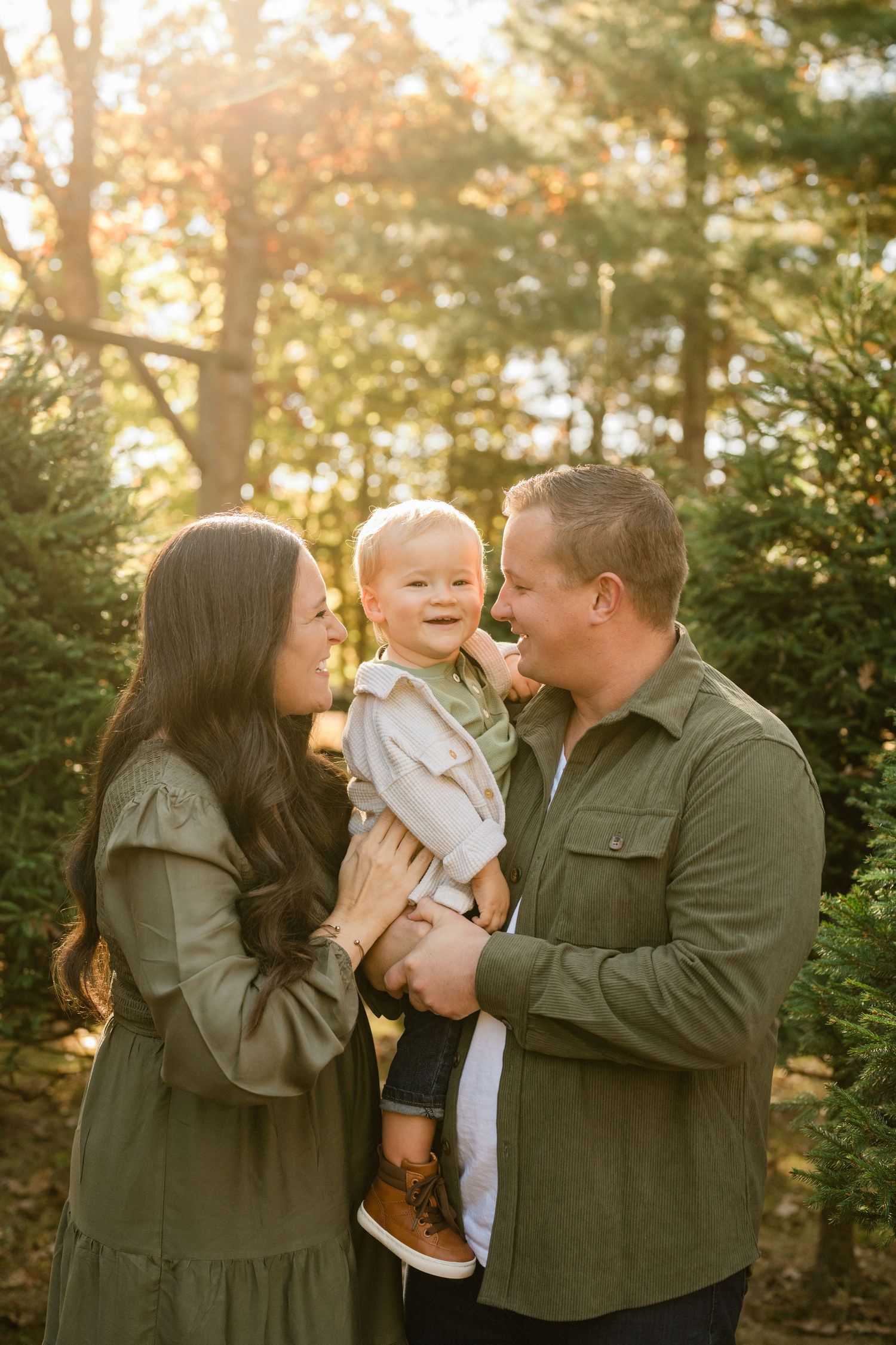 Family sharing joyful moment together at sunset among pine trees.