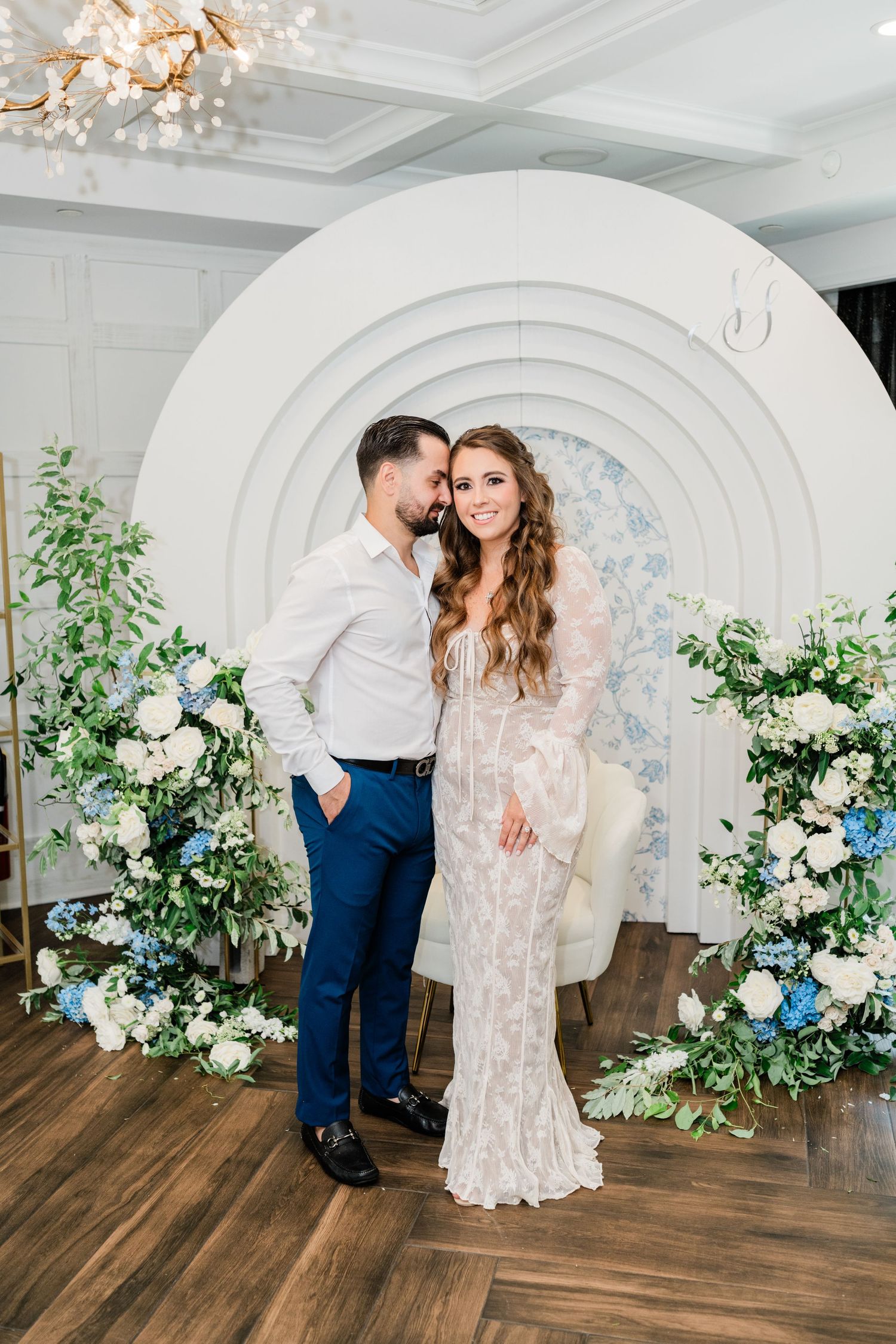 White arched backdrop decorated with flowers and greenery for a wedding photoshoot.