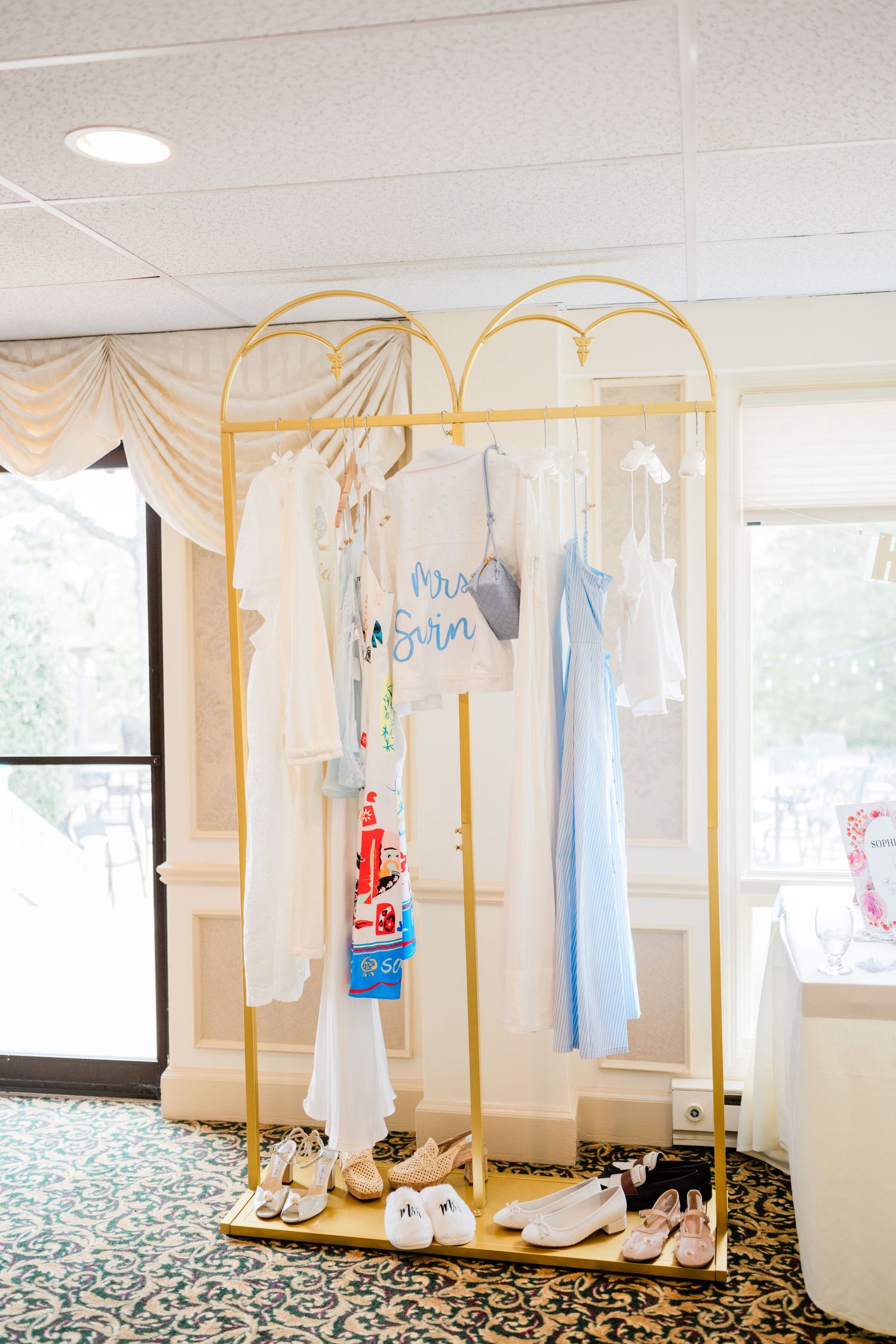 Gold clothing racks displaying formal attire in a bright dressing room setting.