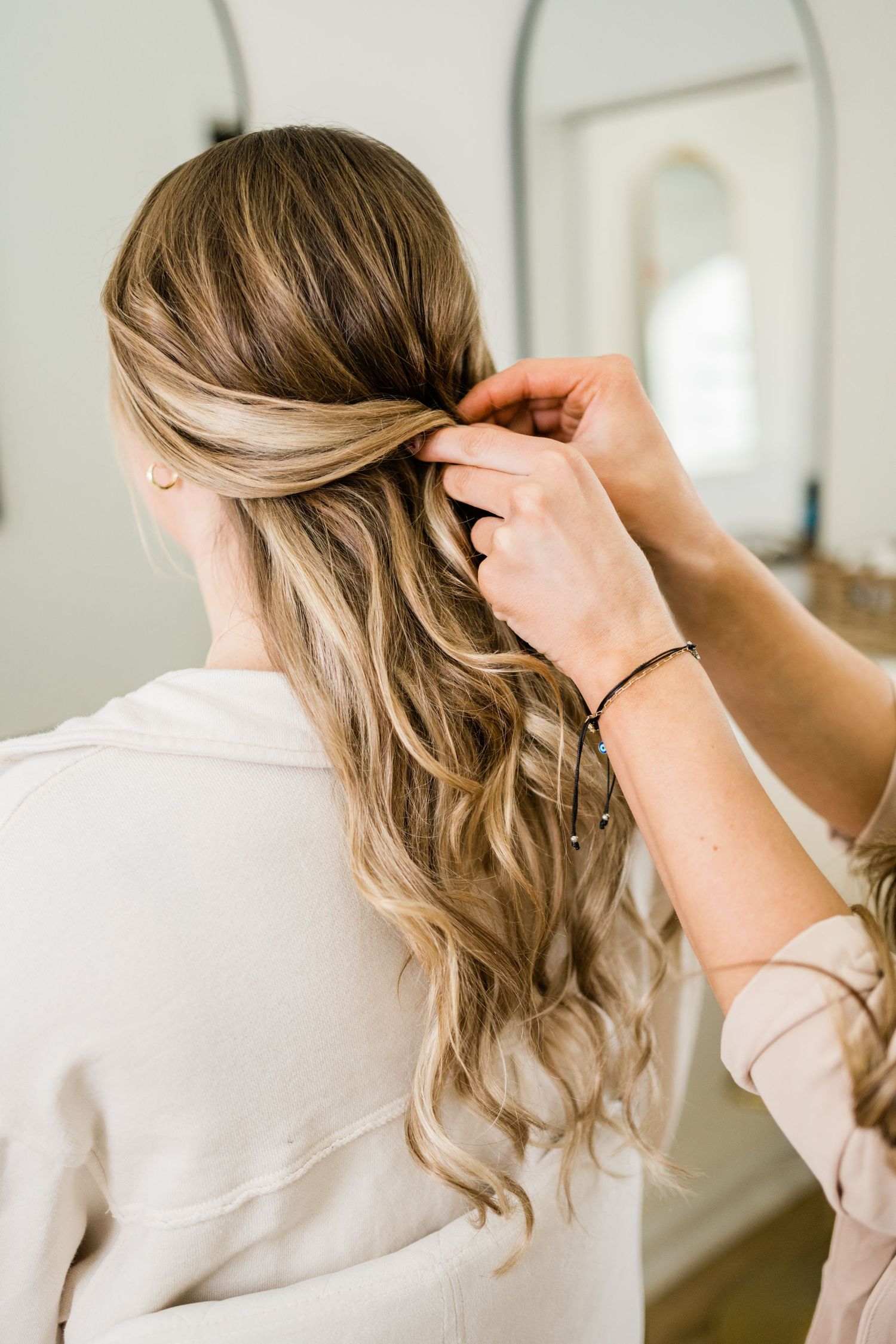 Hair styling demonstration showing wavy hairstyle techniques from behind.
