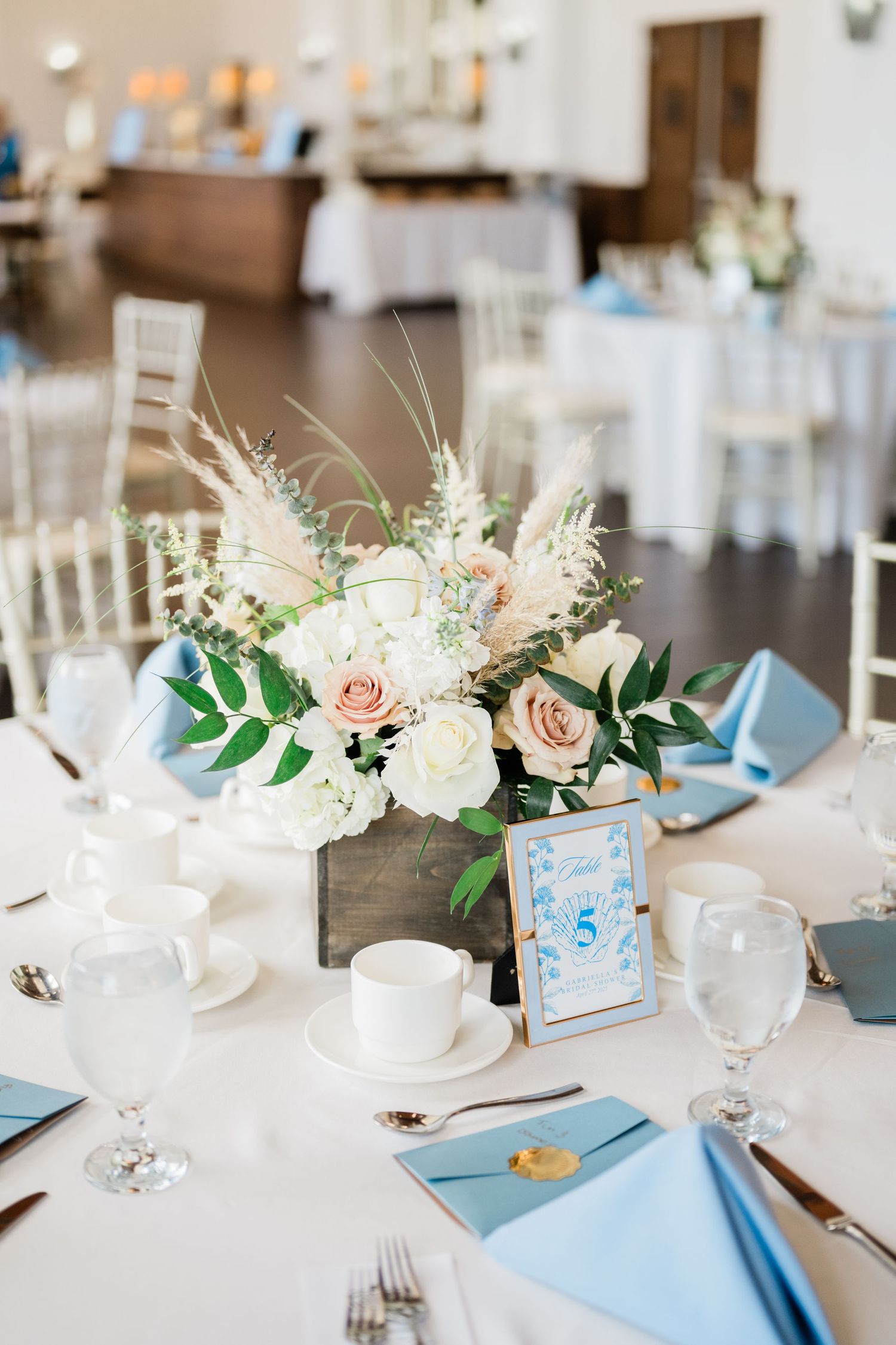 Elegant wedding table settings with white and peach floral centerpieces and light blue accents.