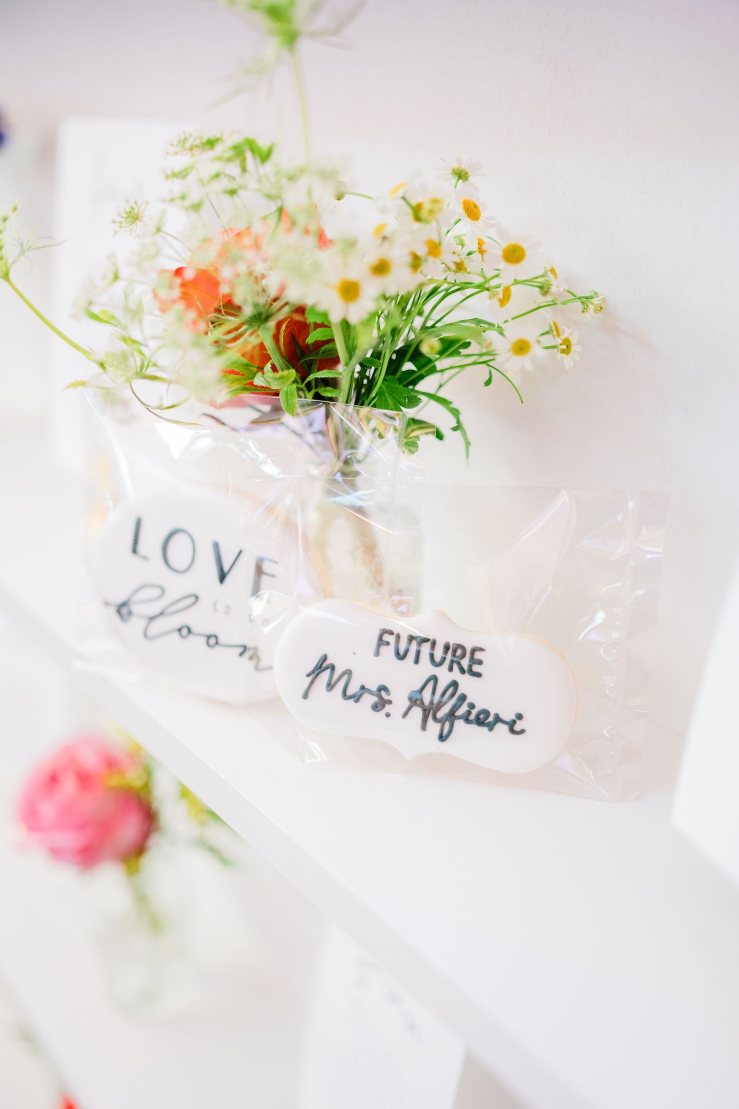 Small glass vases with handwritten labels and fresh flowers for event decoration.