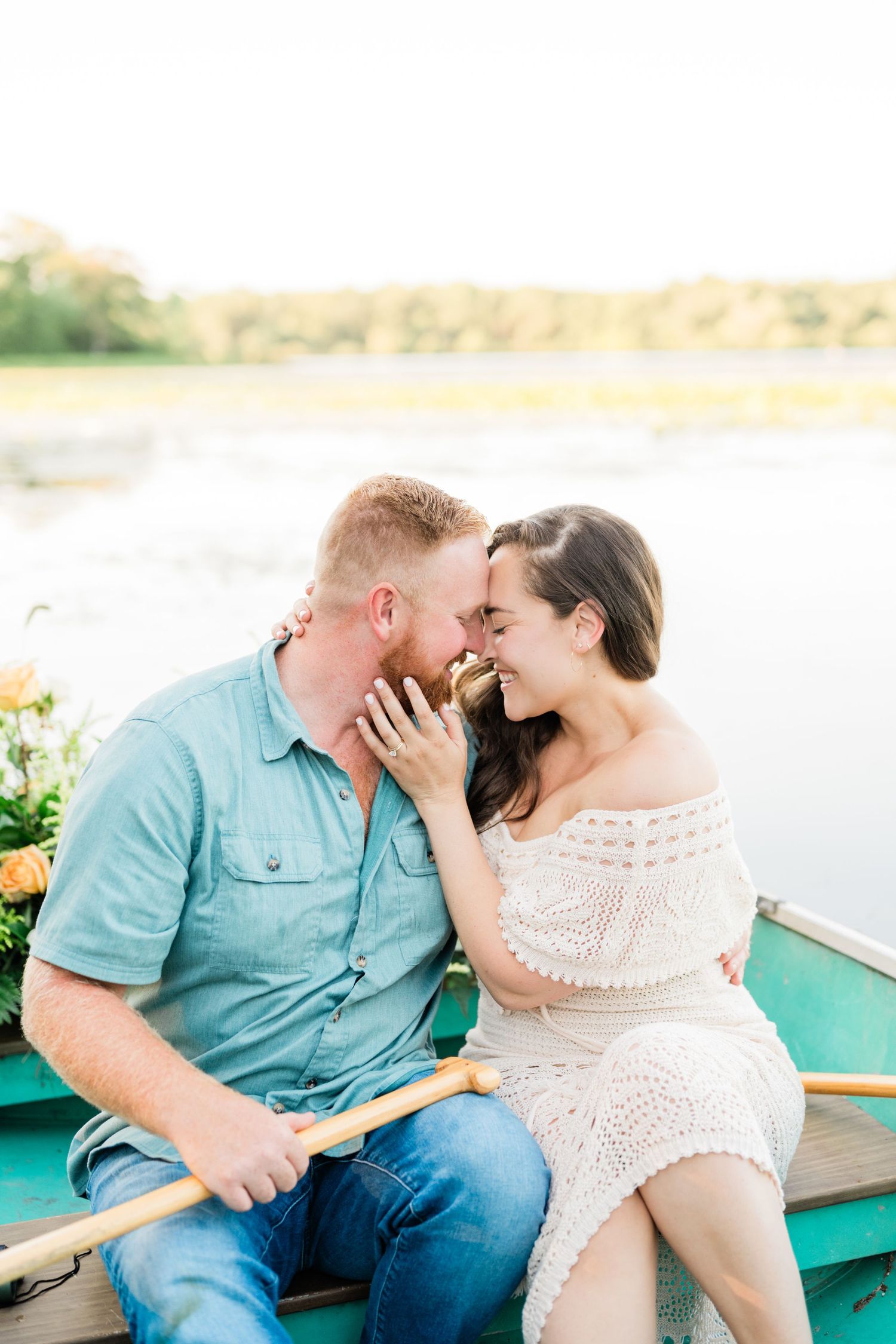 Romantic couple sharing intimate moments in a rowboat on a sunny lake.