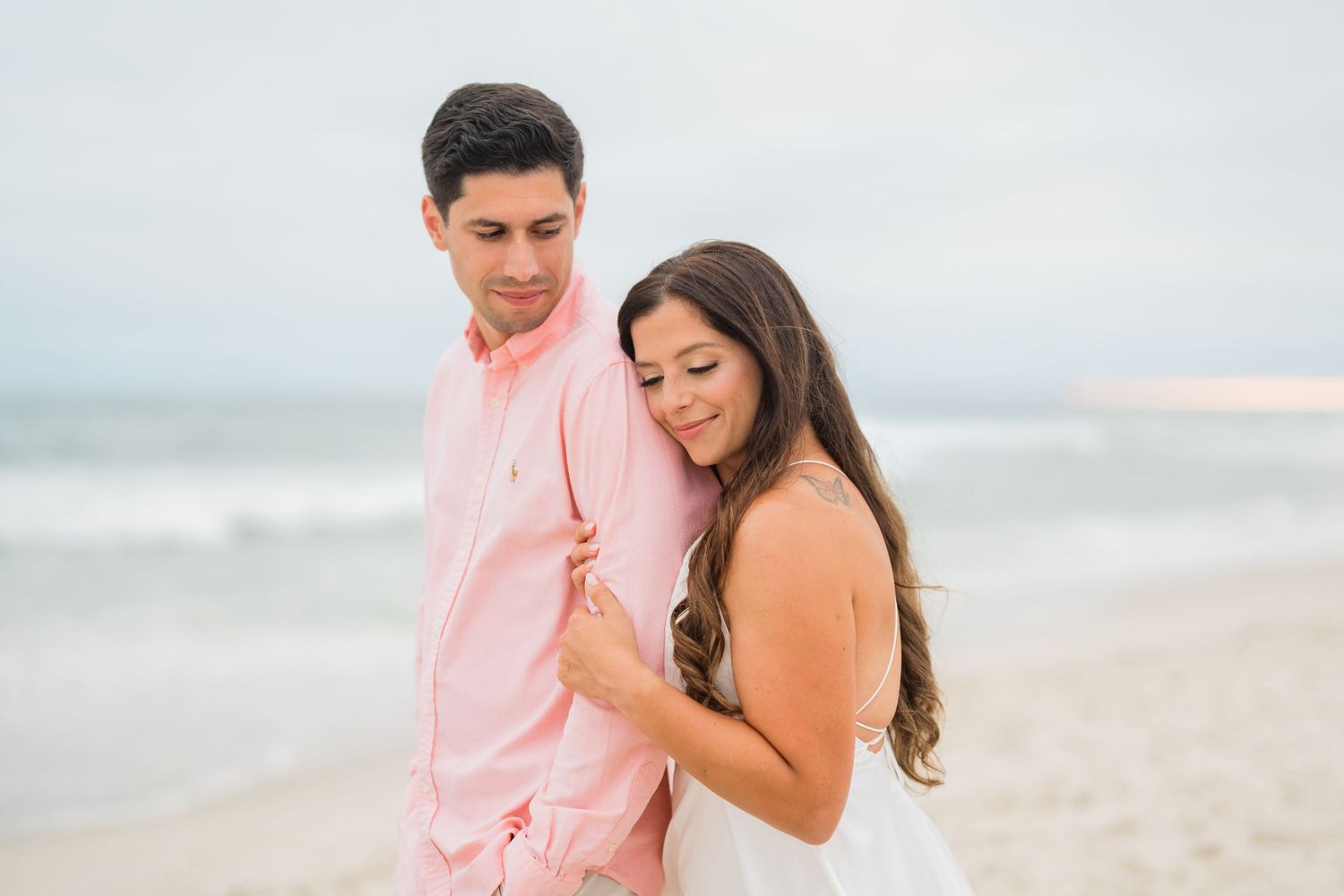 Couple embracing on a sandy beach at sunset.