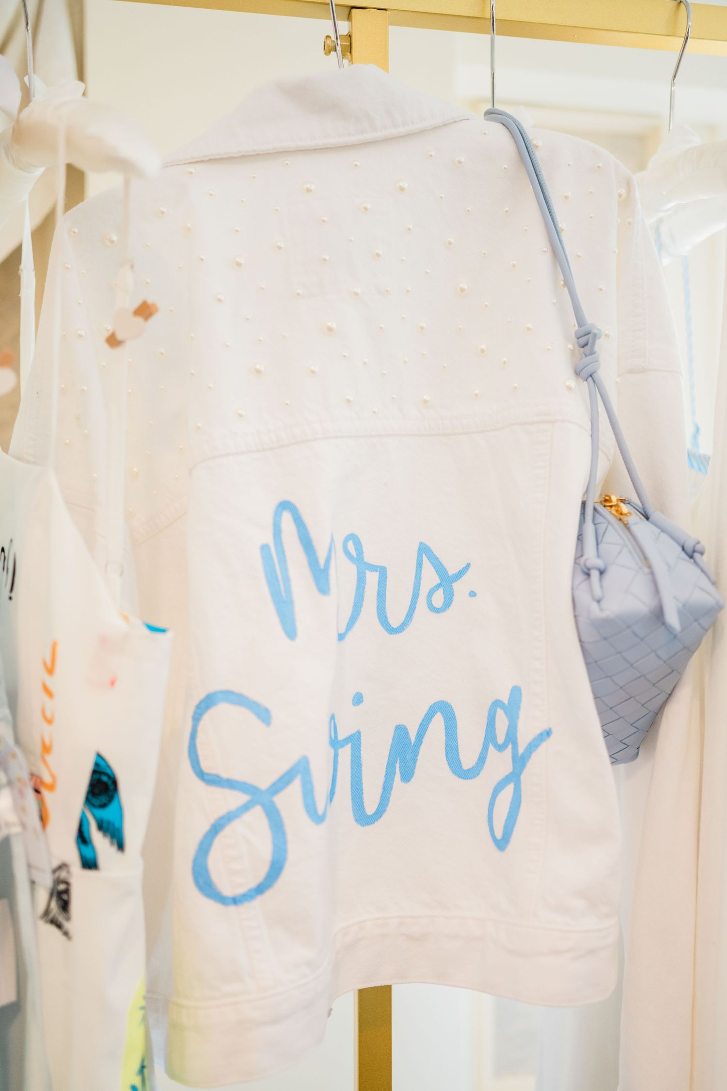 White and blue wedding dresses hanging on display with cursive text decorations.