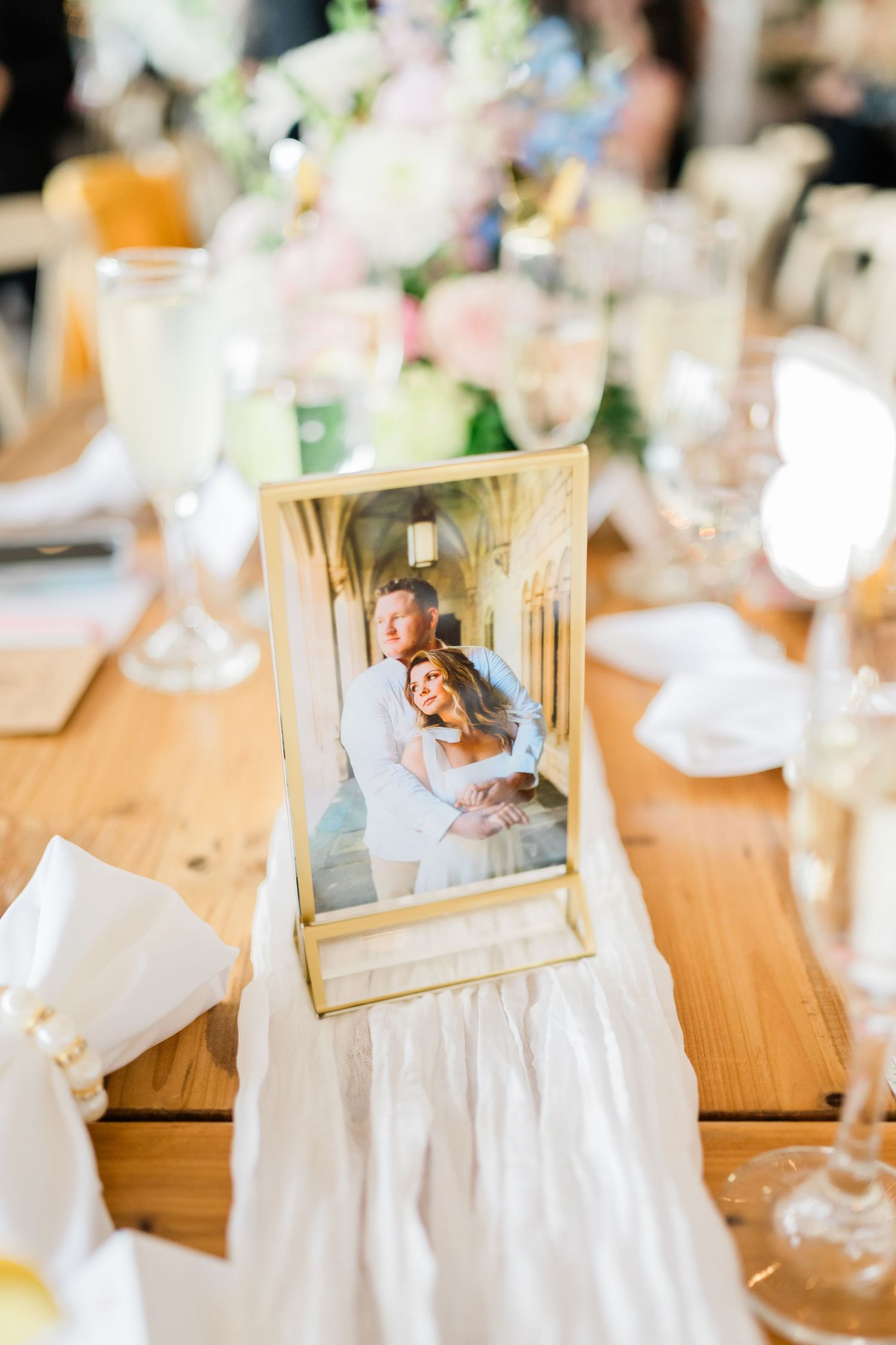 Wedding table settings with framed photographs and white floral centerpieces.
