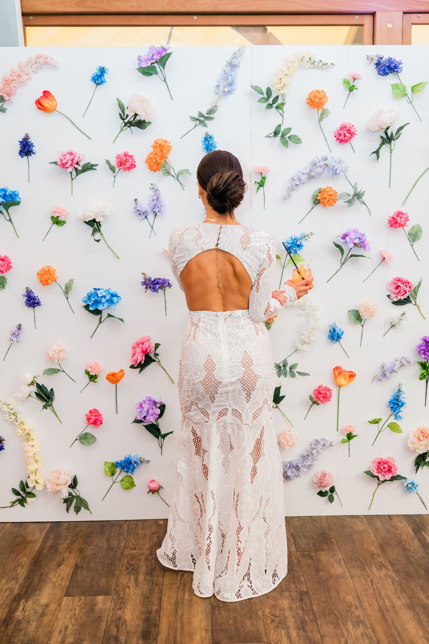 Lace wedding dress photographed against floral decorated white backdrop.