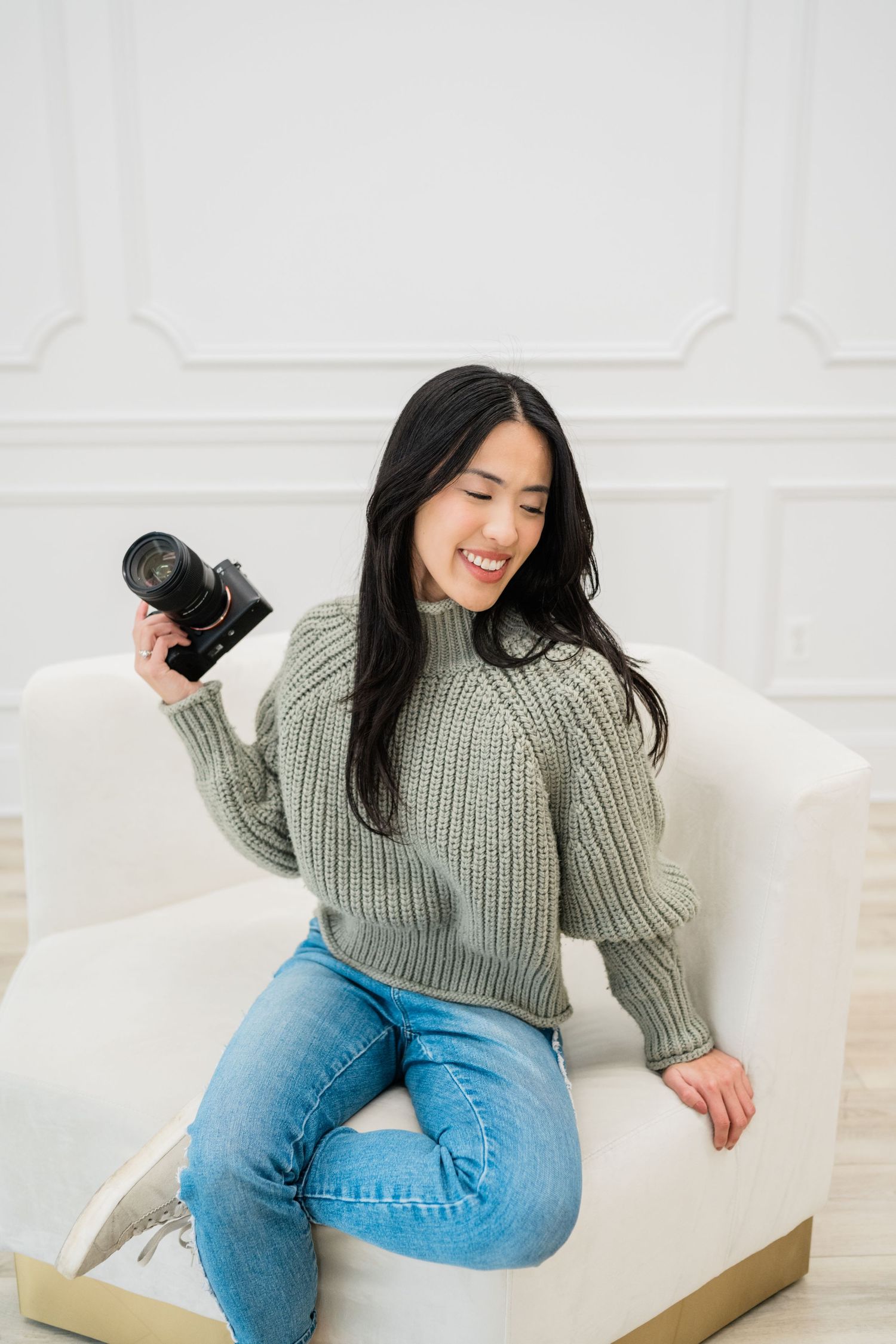 Casual portrait session with photographer holding camera on white couch.