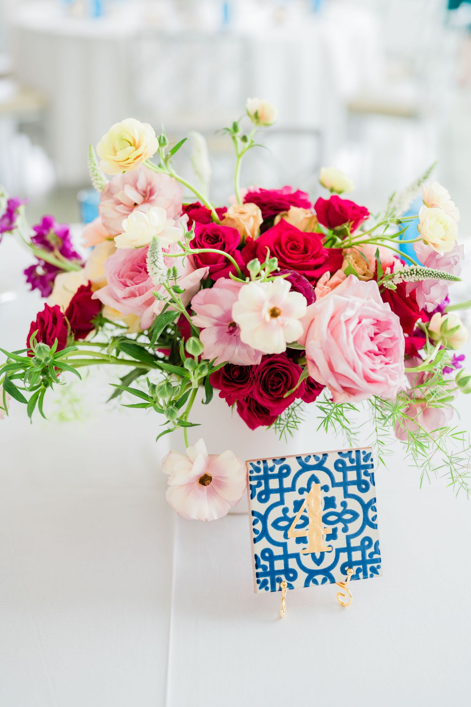Pink and red flowers arranged in blue and white patterned vases for table decor.