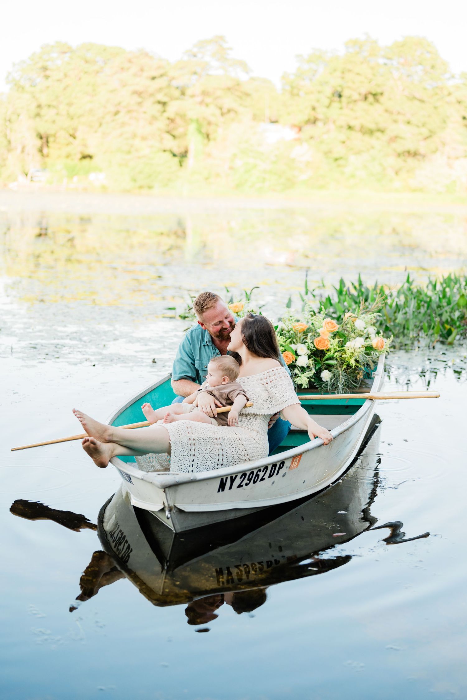 Couple sharing intimate moments in a small rowboat on a peaceful lake.