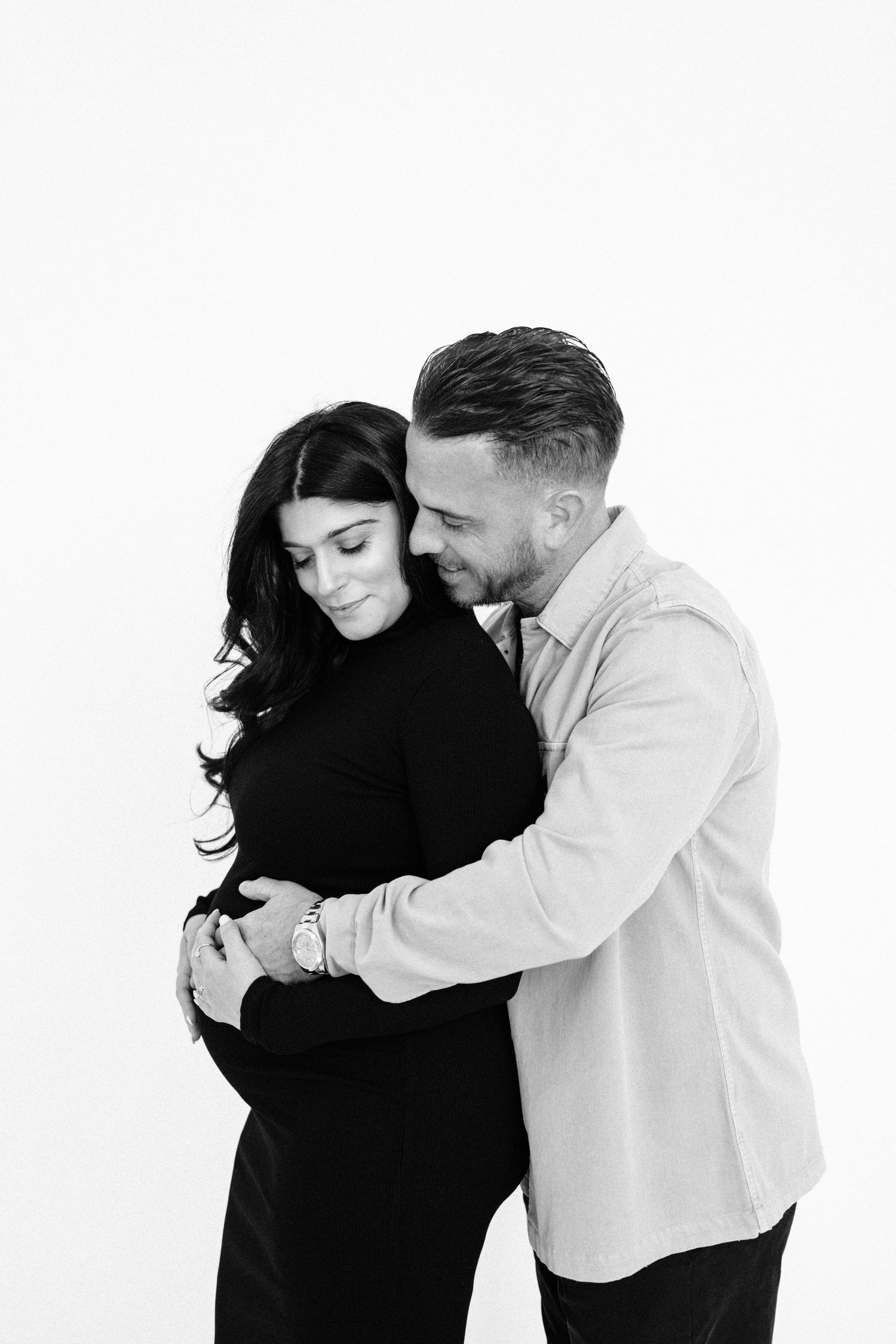 Minimalist black and white maternity portraits showing tender embrace.