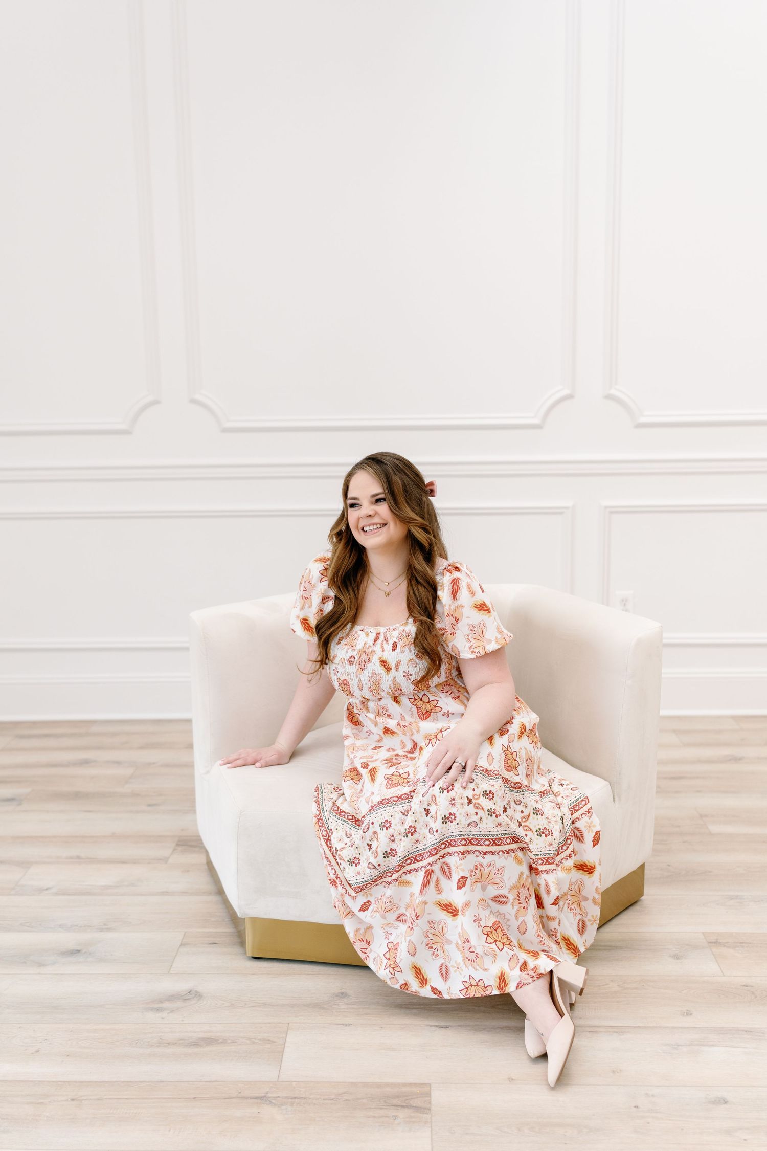 Floral dress photoshoot in bright white studio with gold accented furniture.