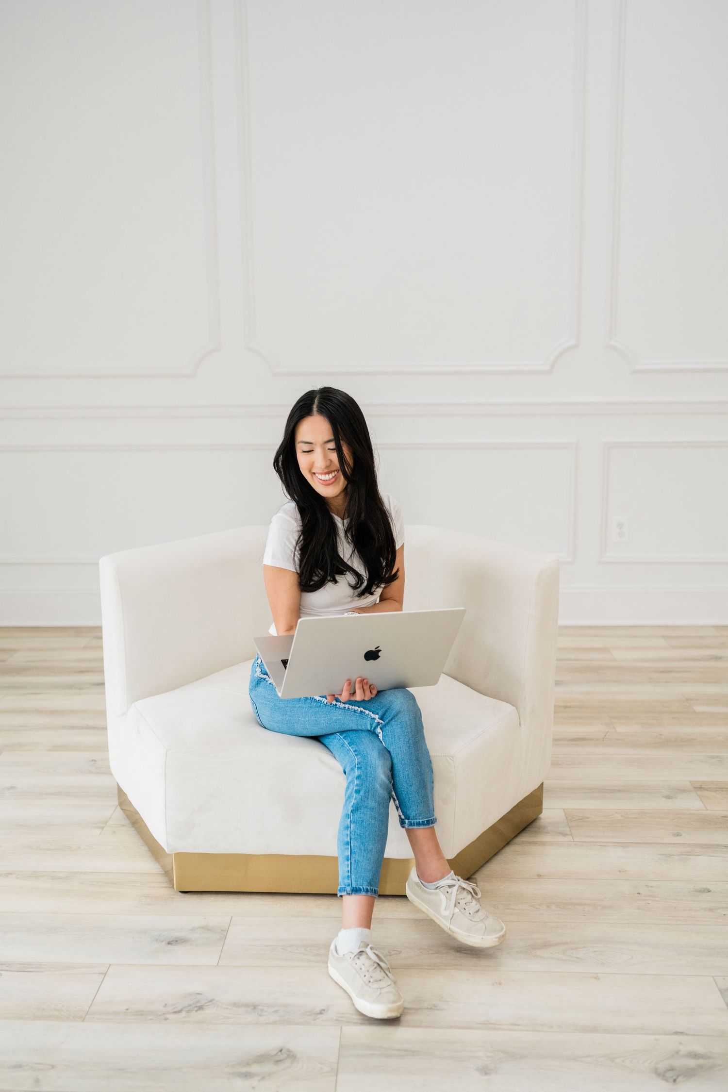 Casual lifestyle photos of person working on laptop while sitting on white couch.