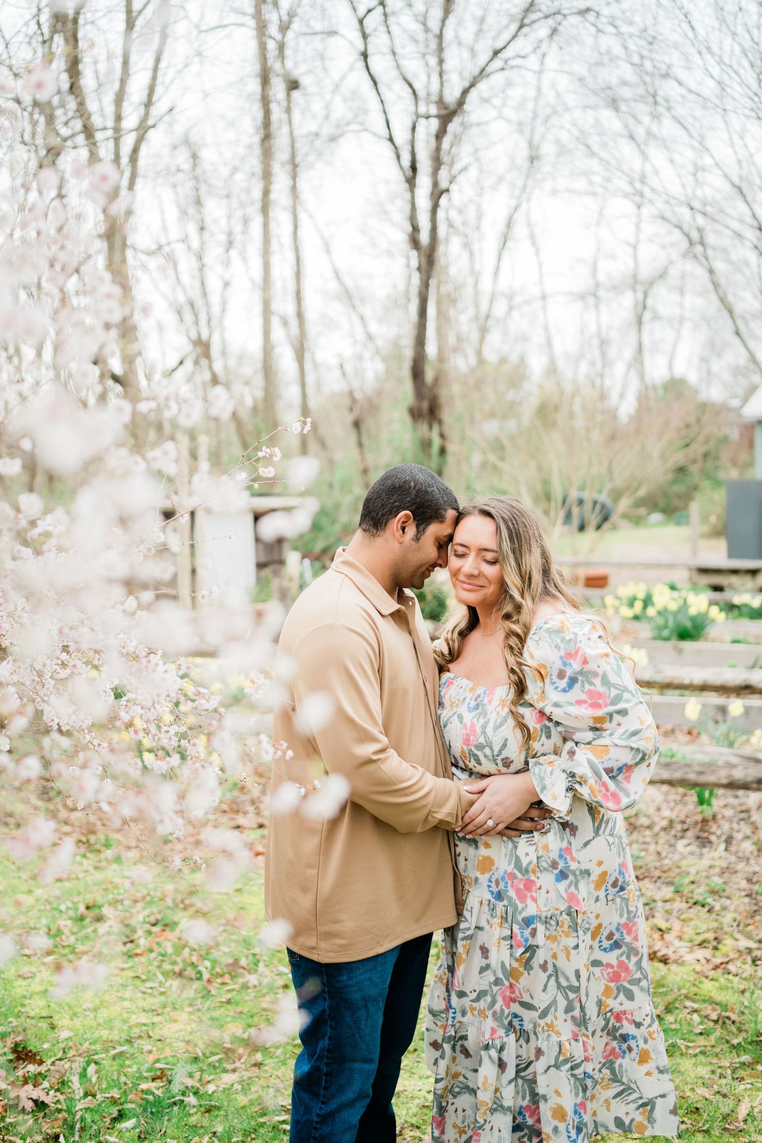 Romantic outdoor maternity photoshoot among blooming spring trees.