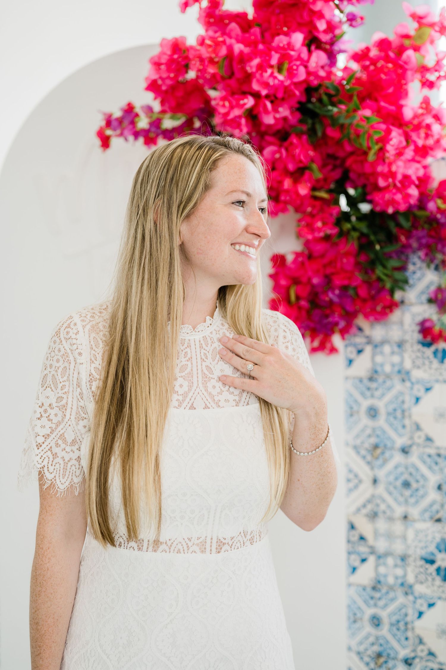 Pink bougainvillea flowers create a vibrant backdrop against blue and white tile pattern.