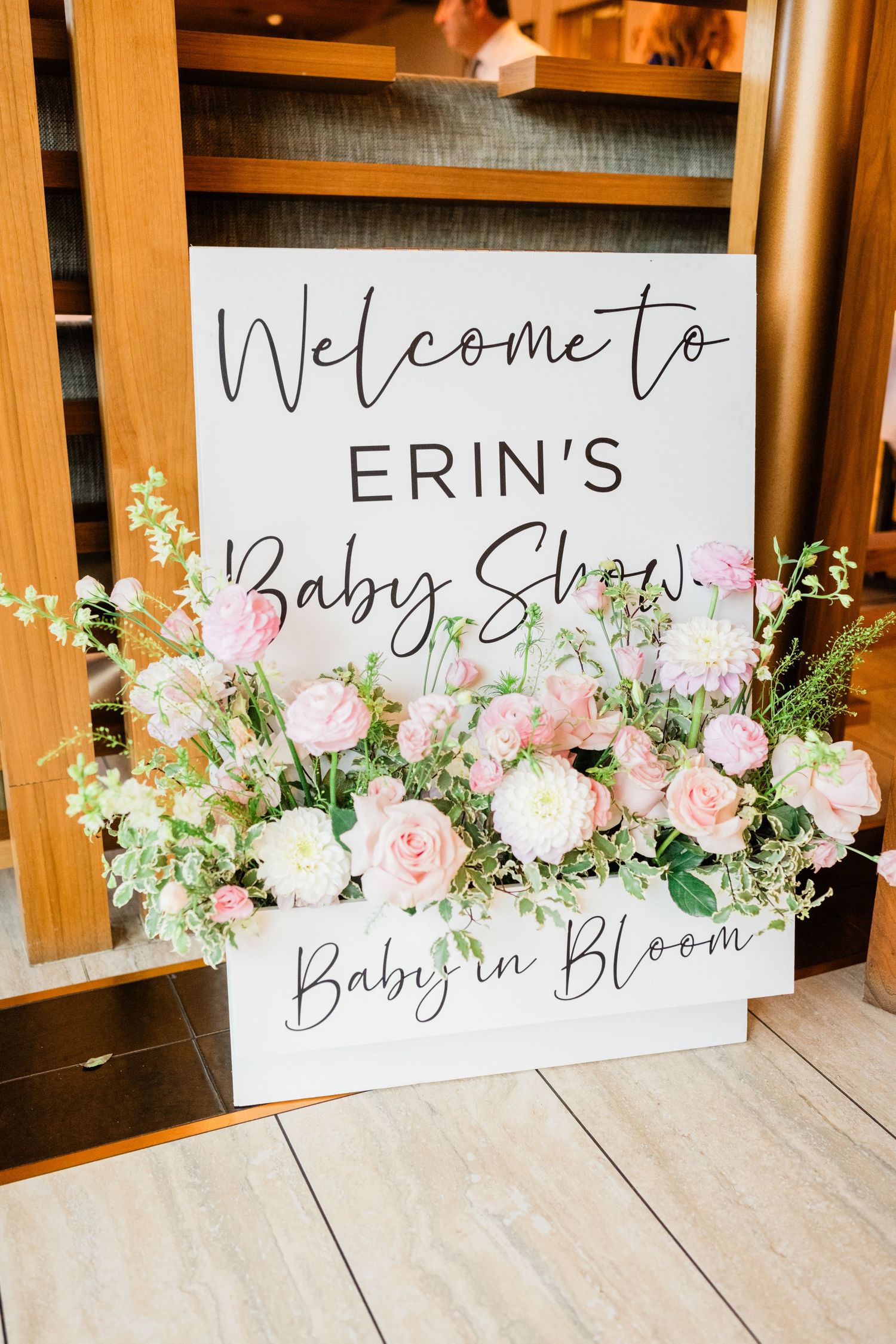 Elegant welcome sign for baby shower featuring pink and white roses with 'Baby in Bloom' text.