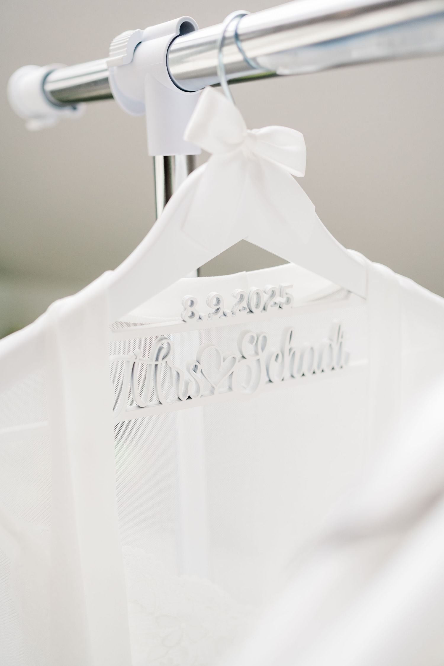 White wedding dress hanger with personalized name text displayed on a clothing rack.