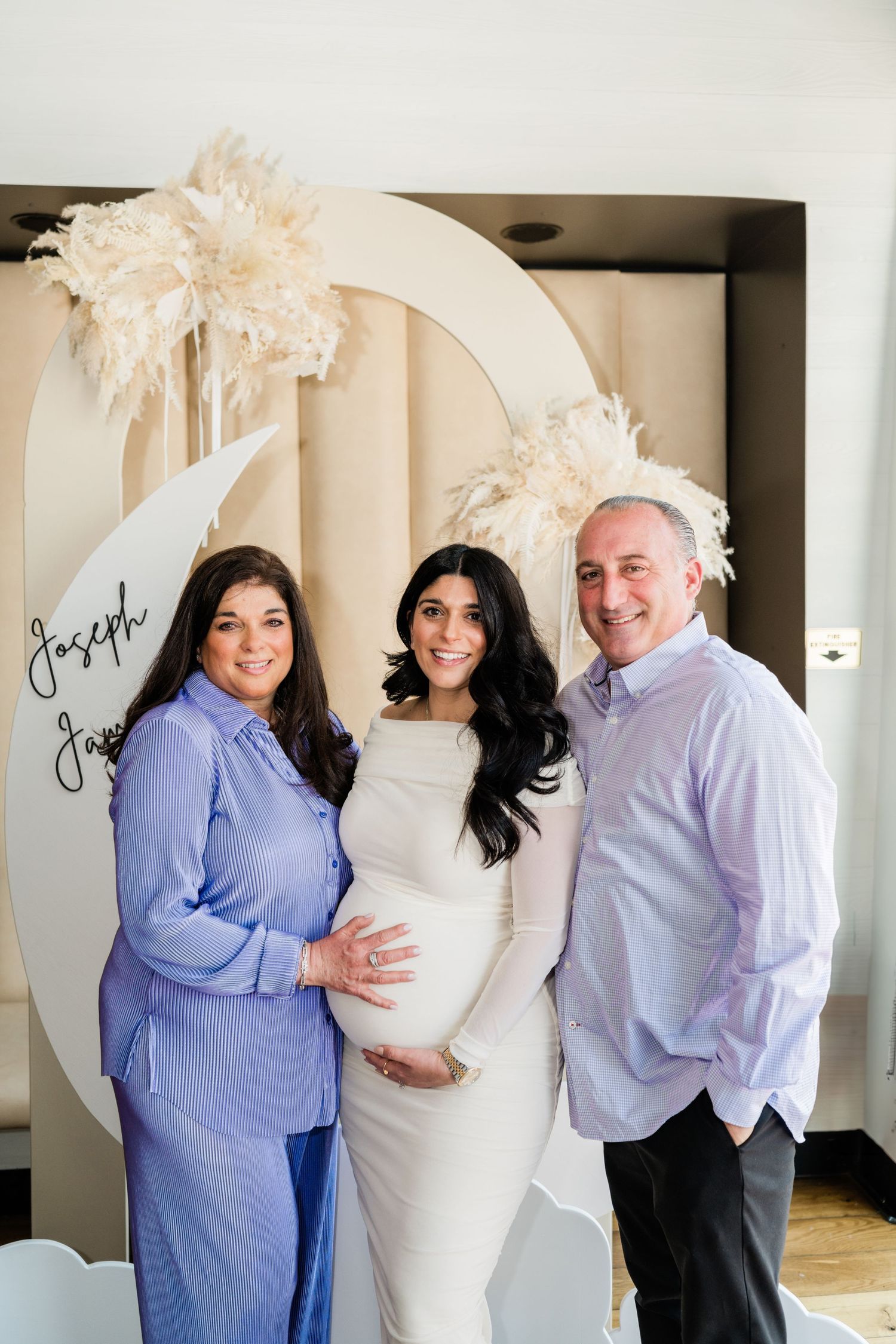 Family maternity photo with decorative moon backdrop and neutral color scheme.