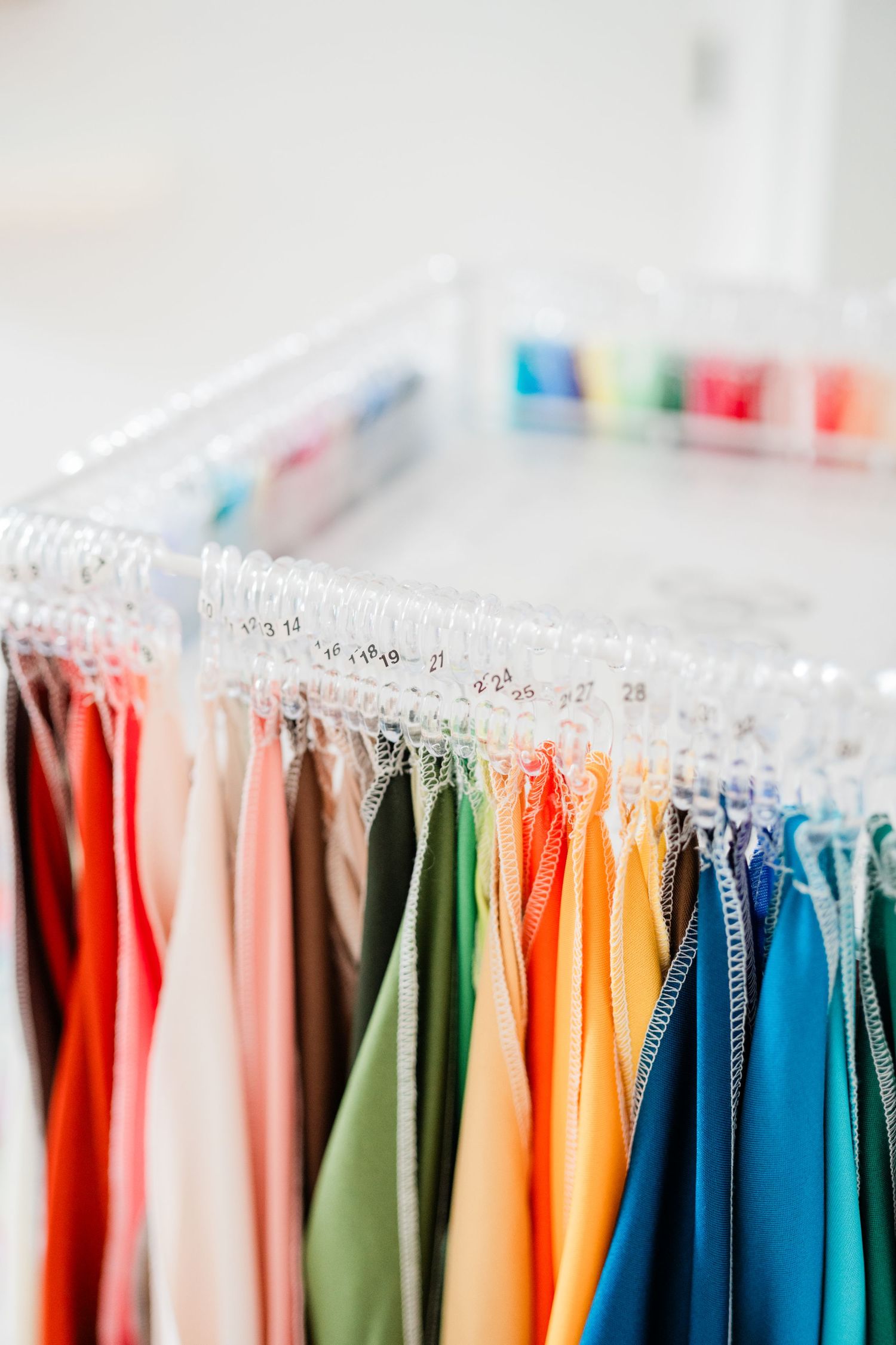 Colorful rack of clothing displaying various dresses in rainbow order on hangers.