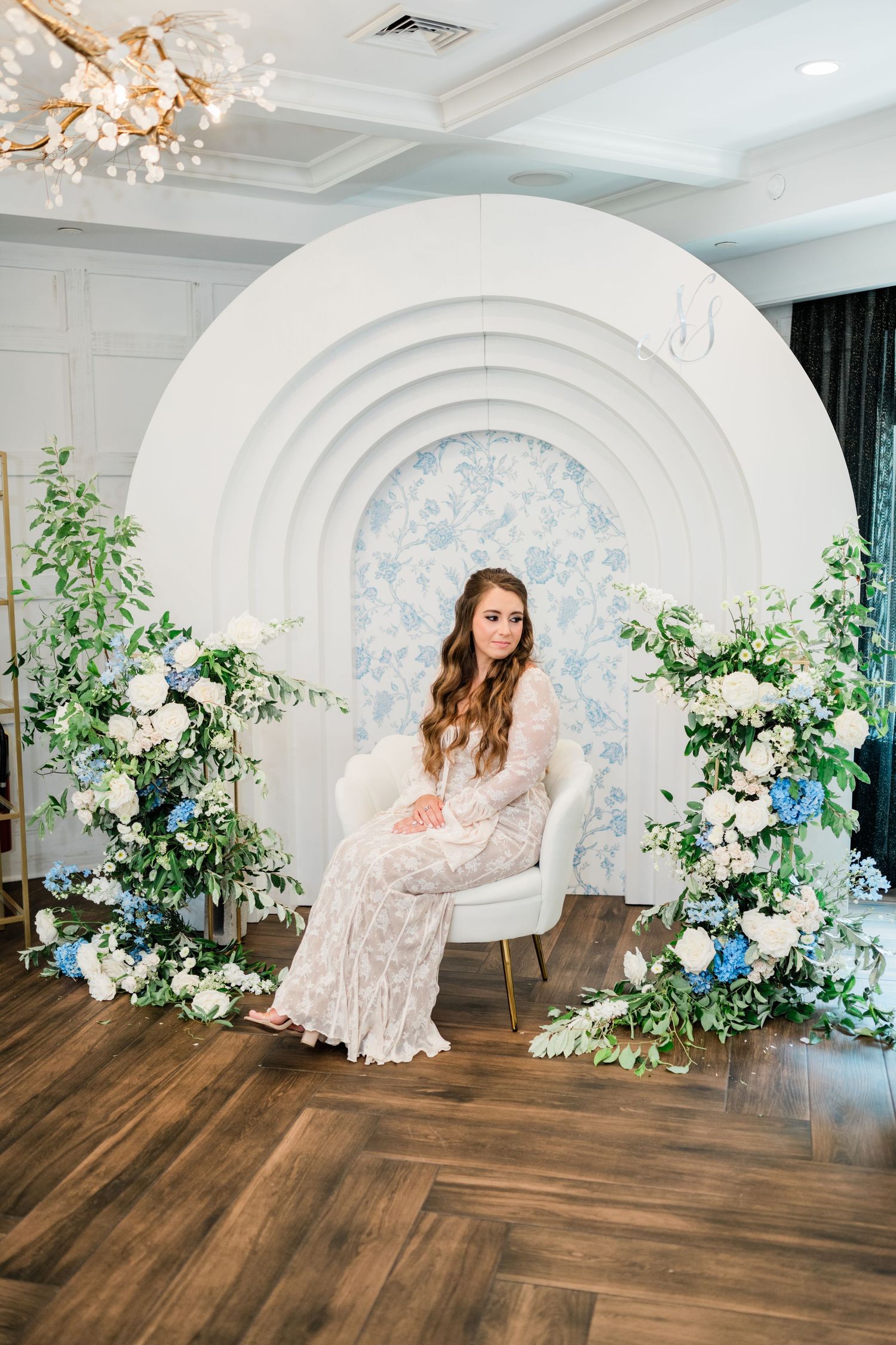 White archway decorated with blue and white flowers against wooden flooring in an elegant venue.
