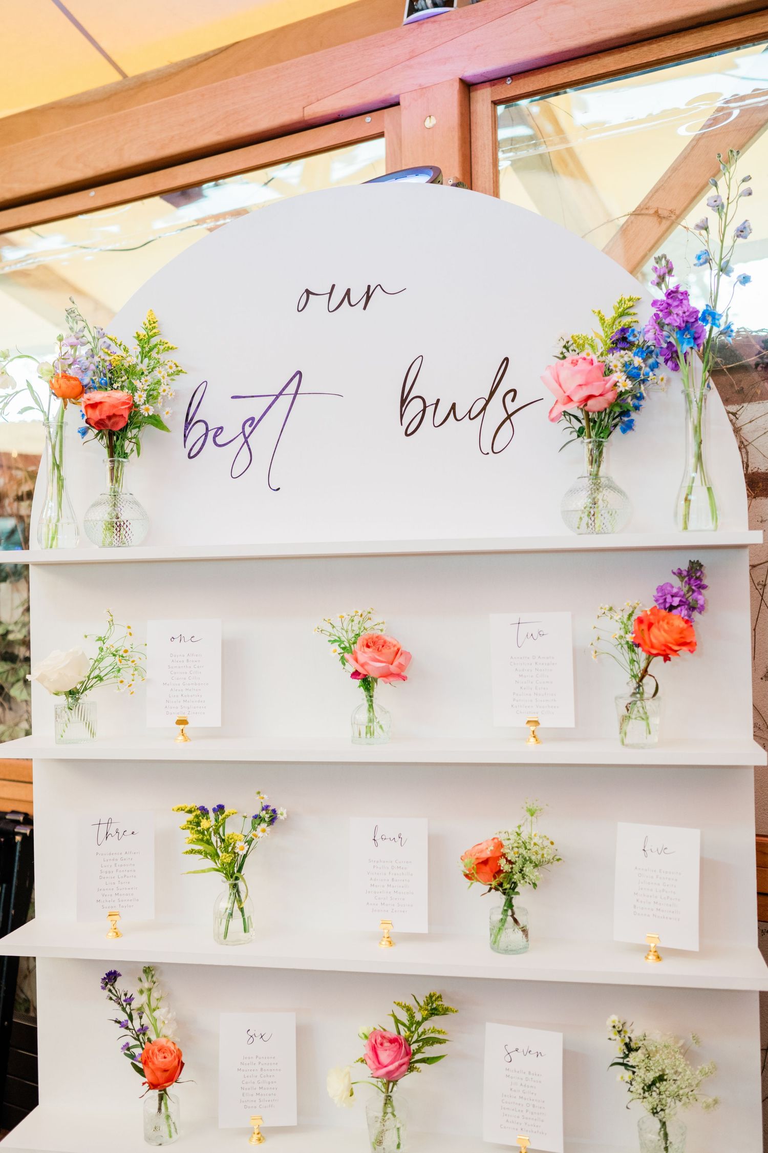 Modern wedding seating chart display with fresh flower vases and handwritten cards.