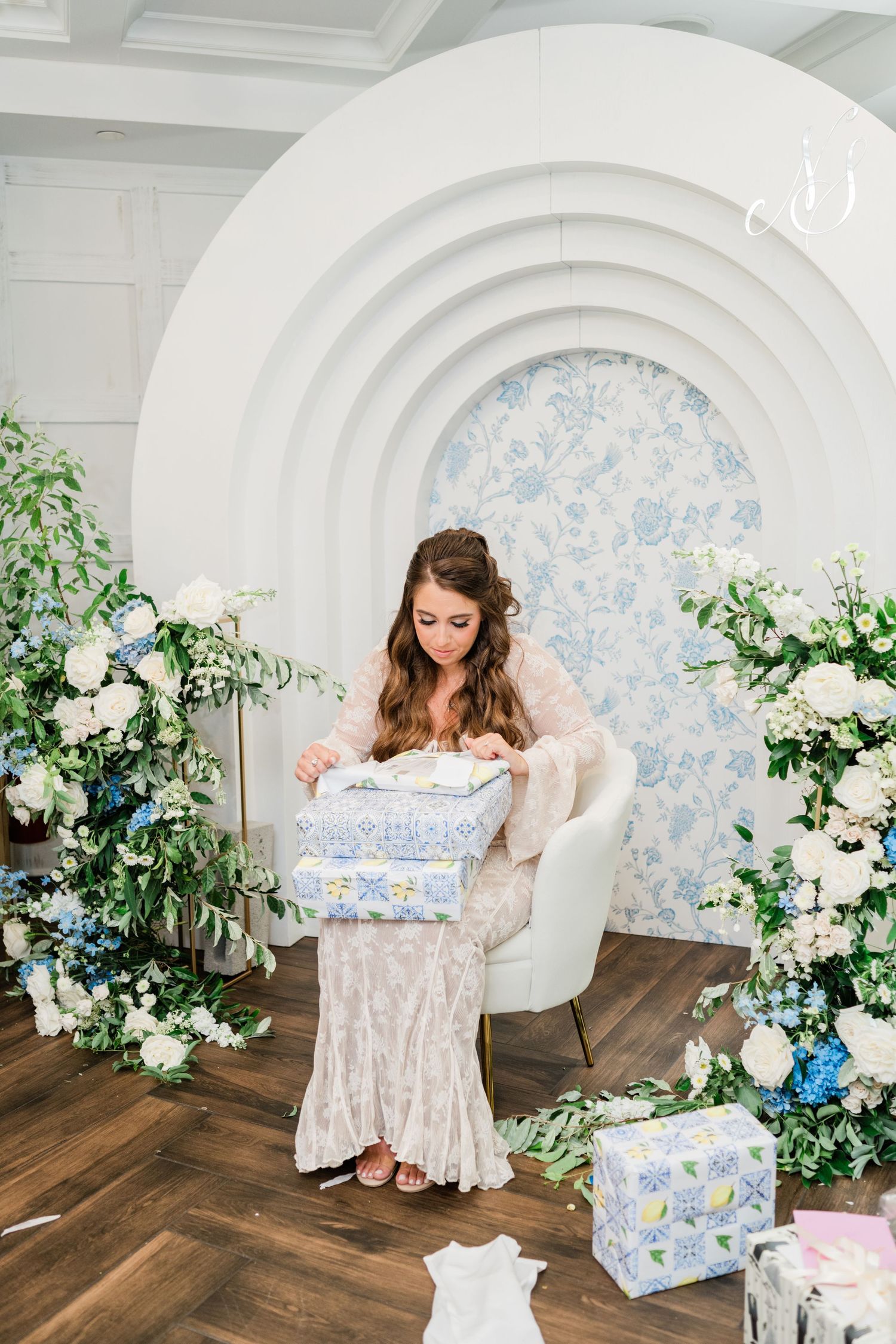 Elegant white arched backdrop with blue floral accents and decorative greenery.