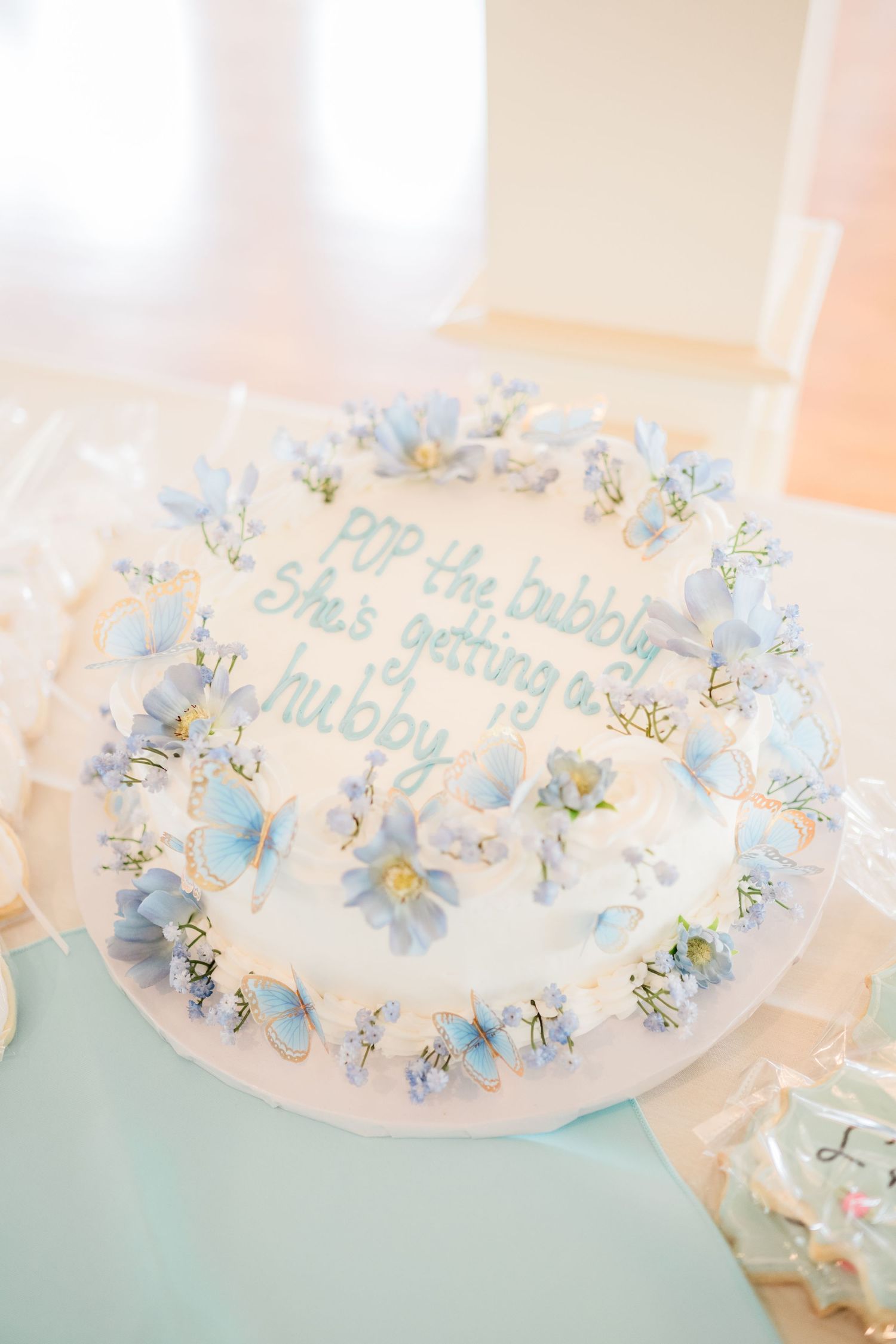 Delicate blue floral decorations adorn a wedding cake with elegant script text.