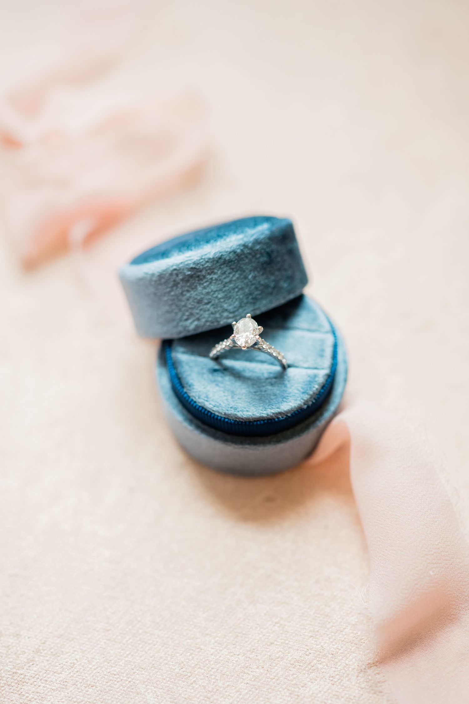 A solitaire diamond engagement ring nestled in a blue velvet ring box.