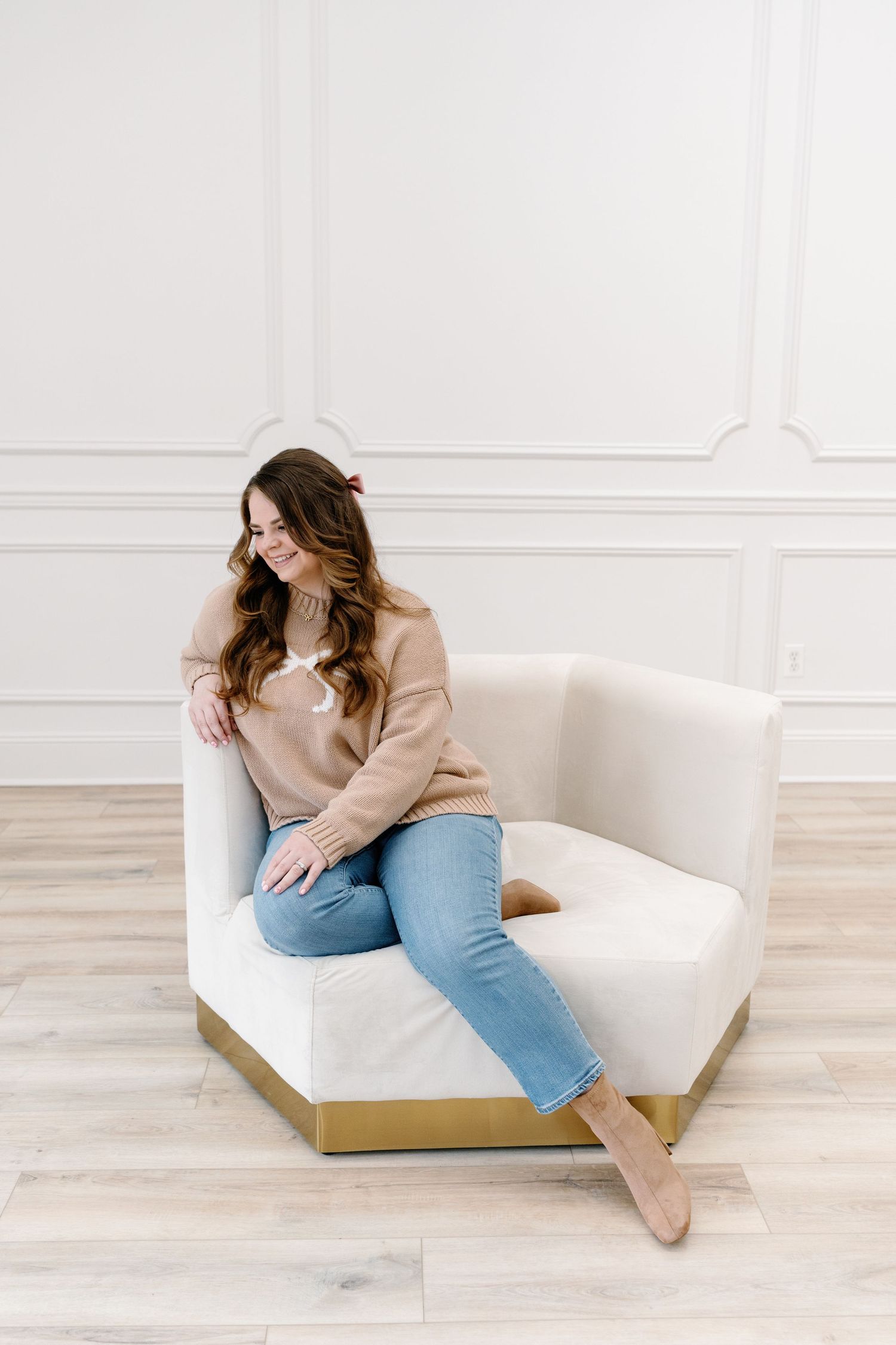 Lifestyle photo session featuring casual lounging poses on a white modern chair in a bright studio setting.
